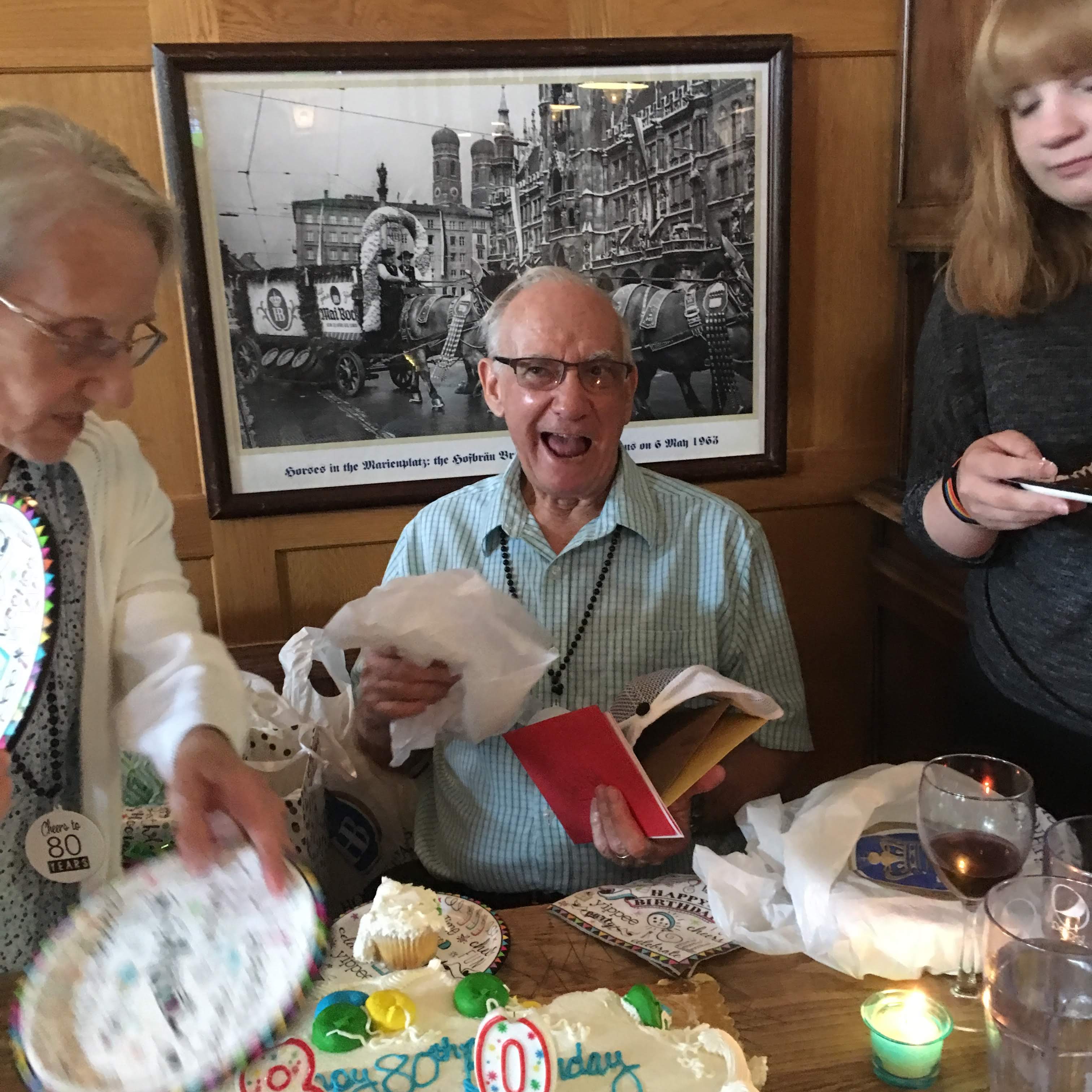 A group of people sitting at a table with a cake and a book