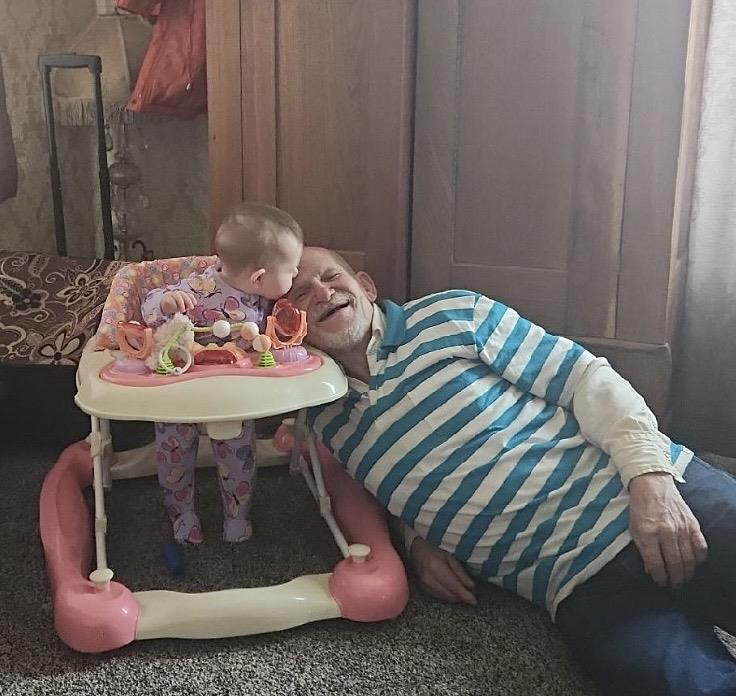 A man lying on the floor next to a baby