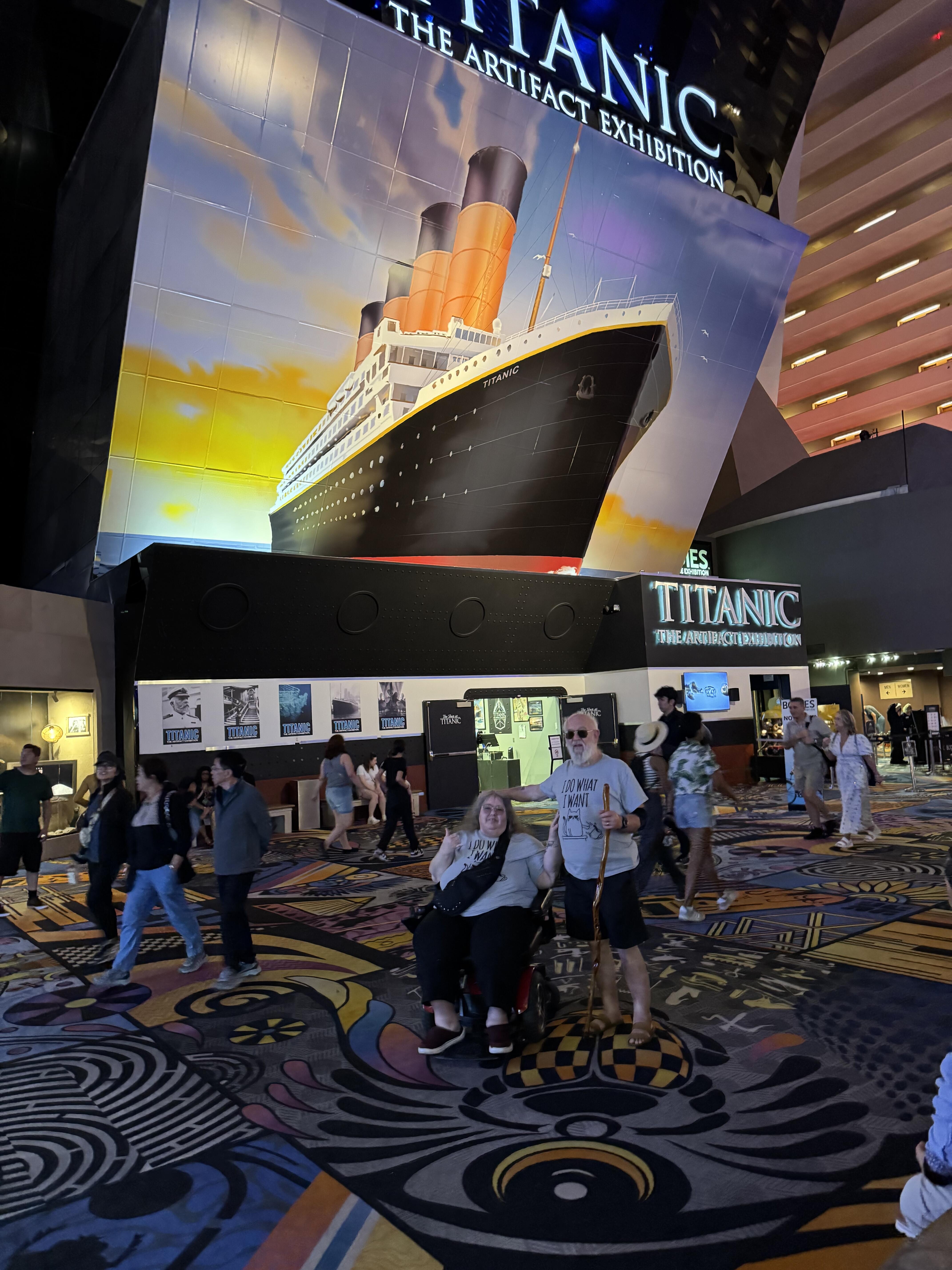 A group of people in a large room with a large ship on the wall