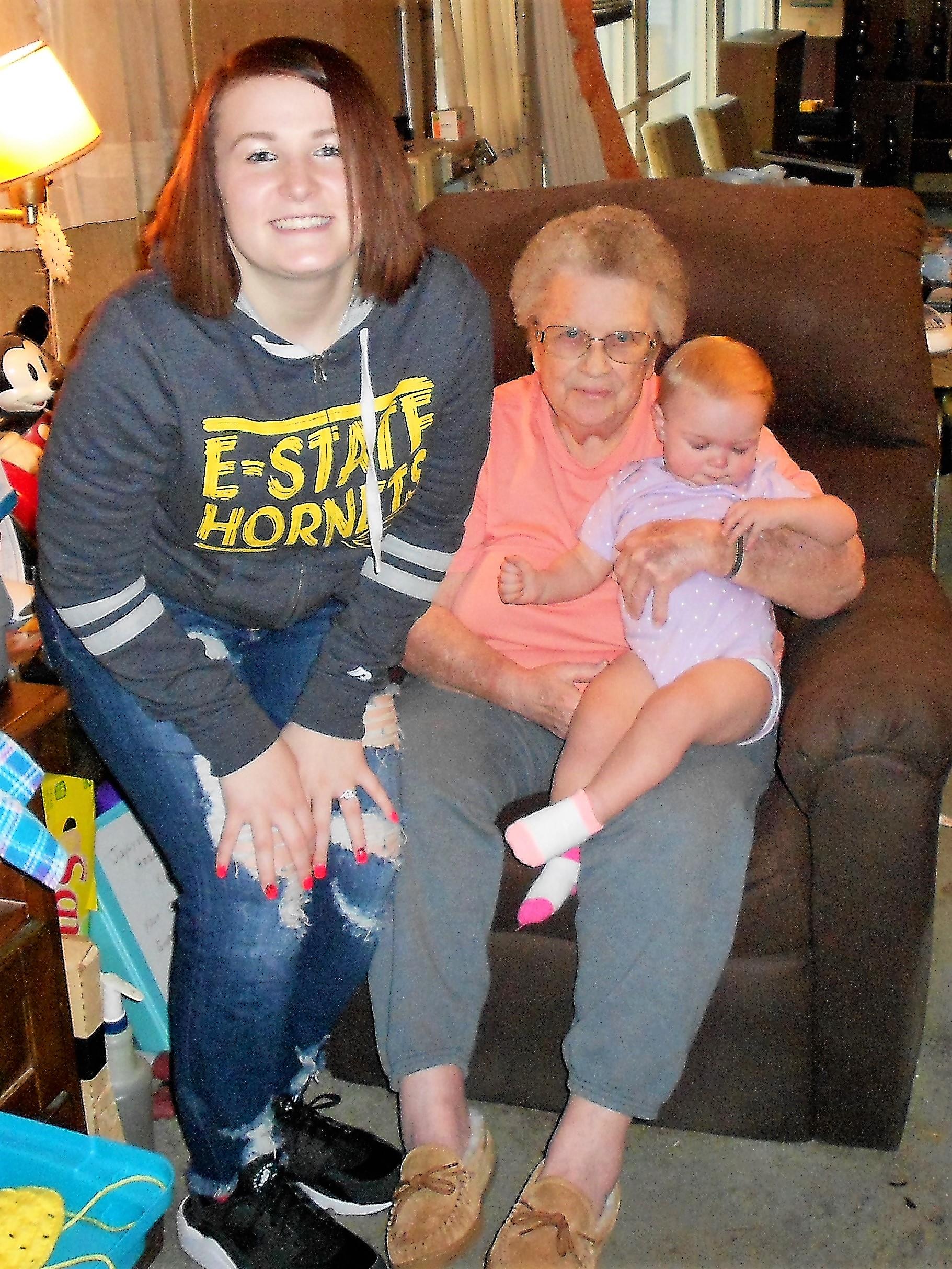A woman holding a baby and sitting in a chair