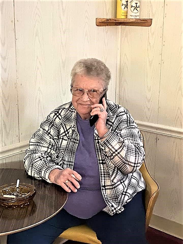 An older woman sitting at a table talking on a cell phone