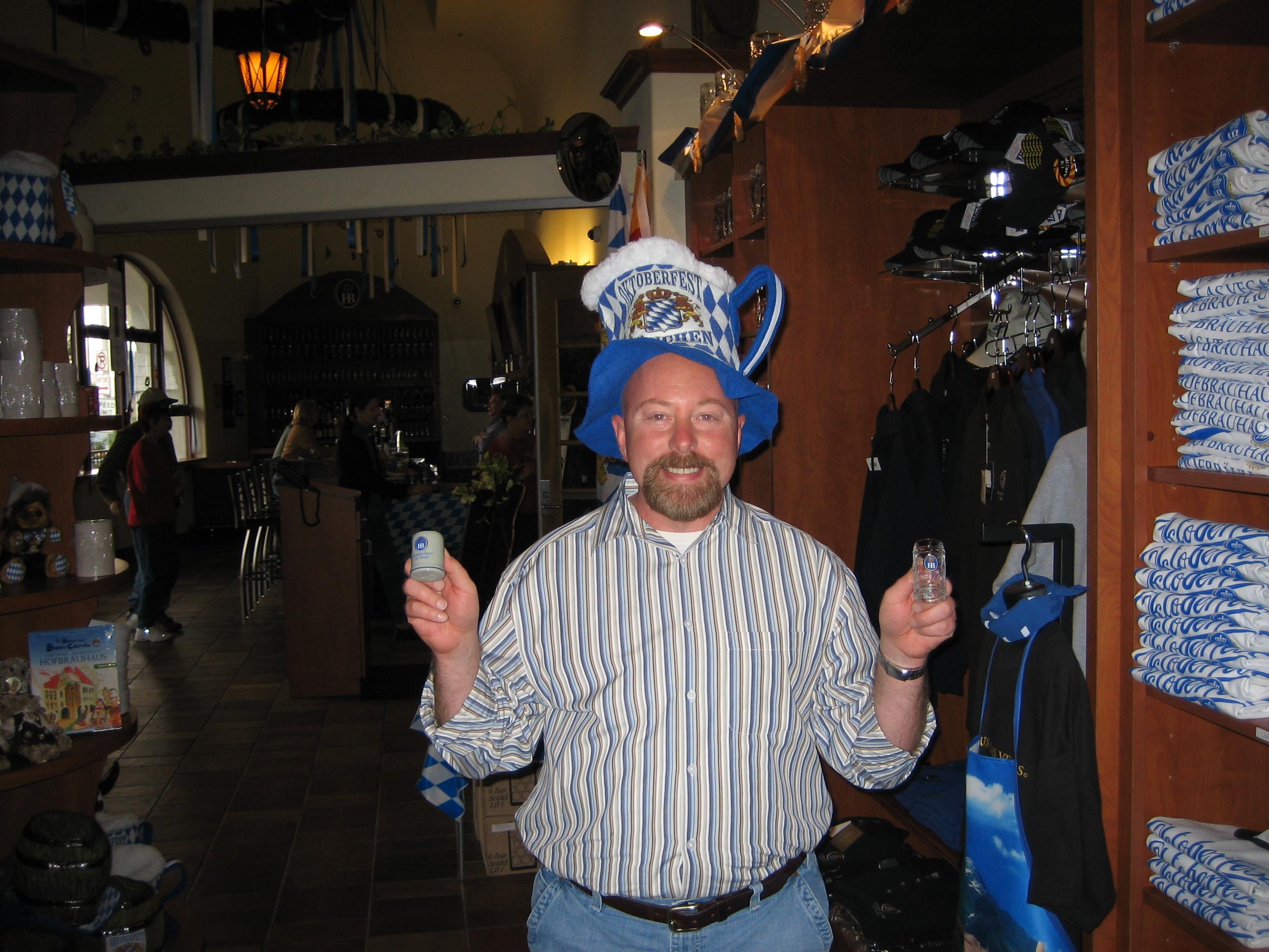 A man wearing a blue hat and holding a bottle and a small glass