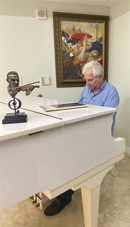 A man sitting at a white piano