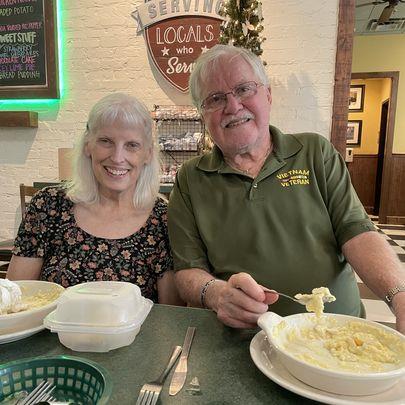 A man and woman sitting at a table with food