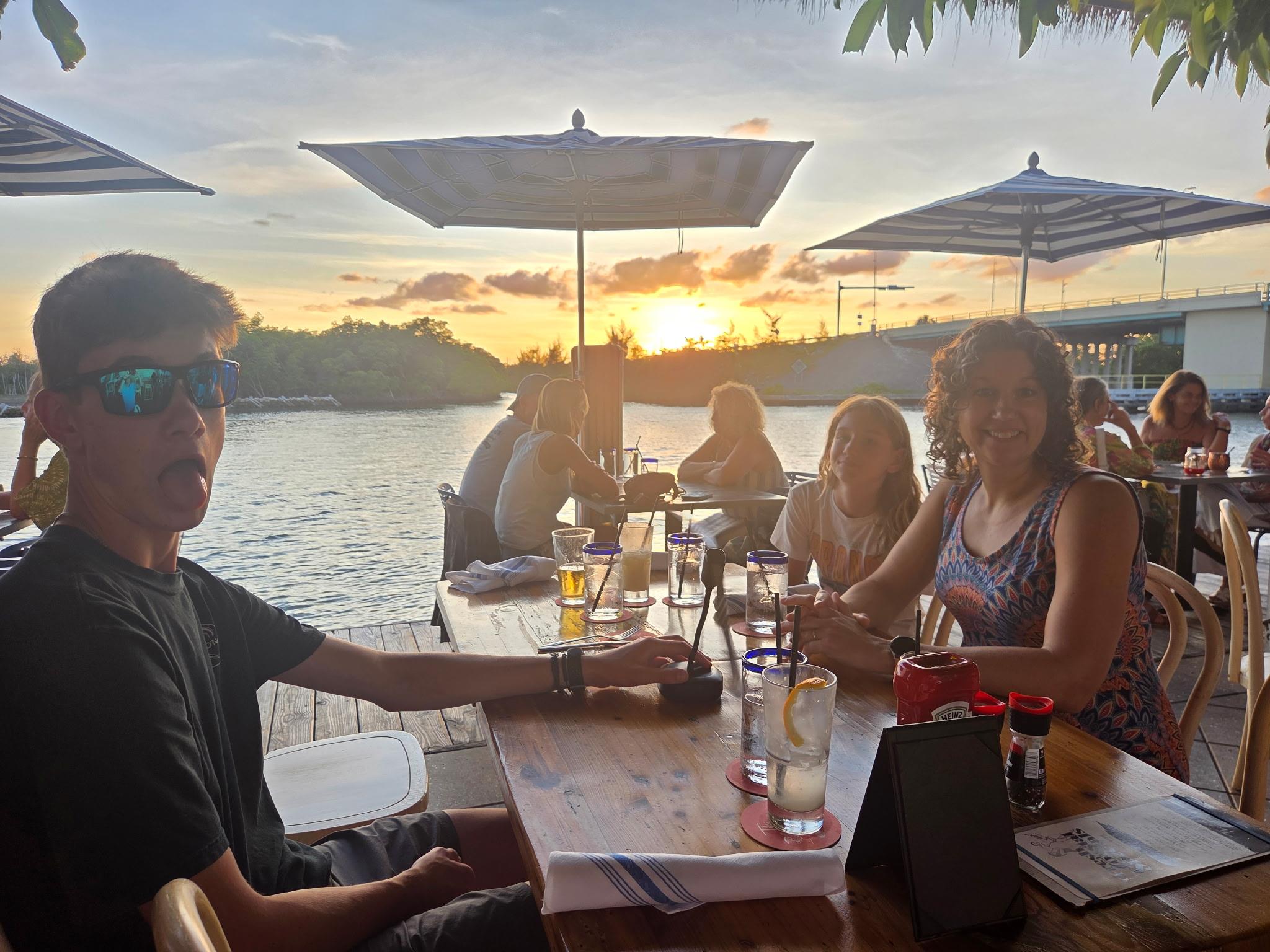 A group of people sitting at a table with drinks and umbrellas