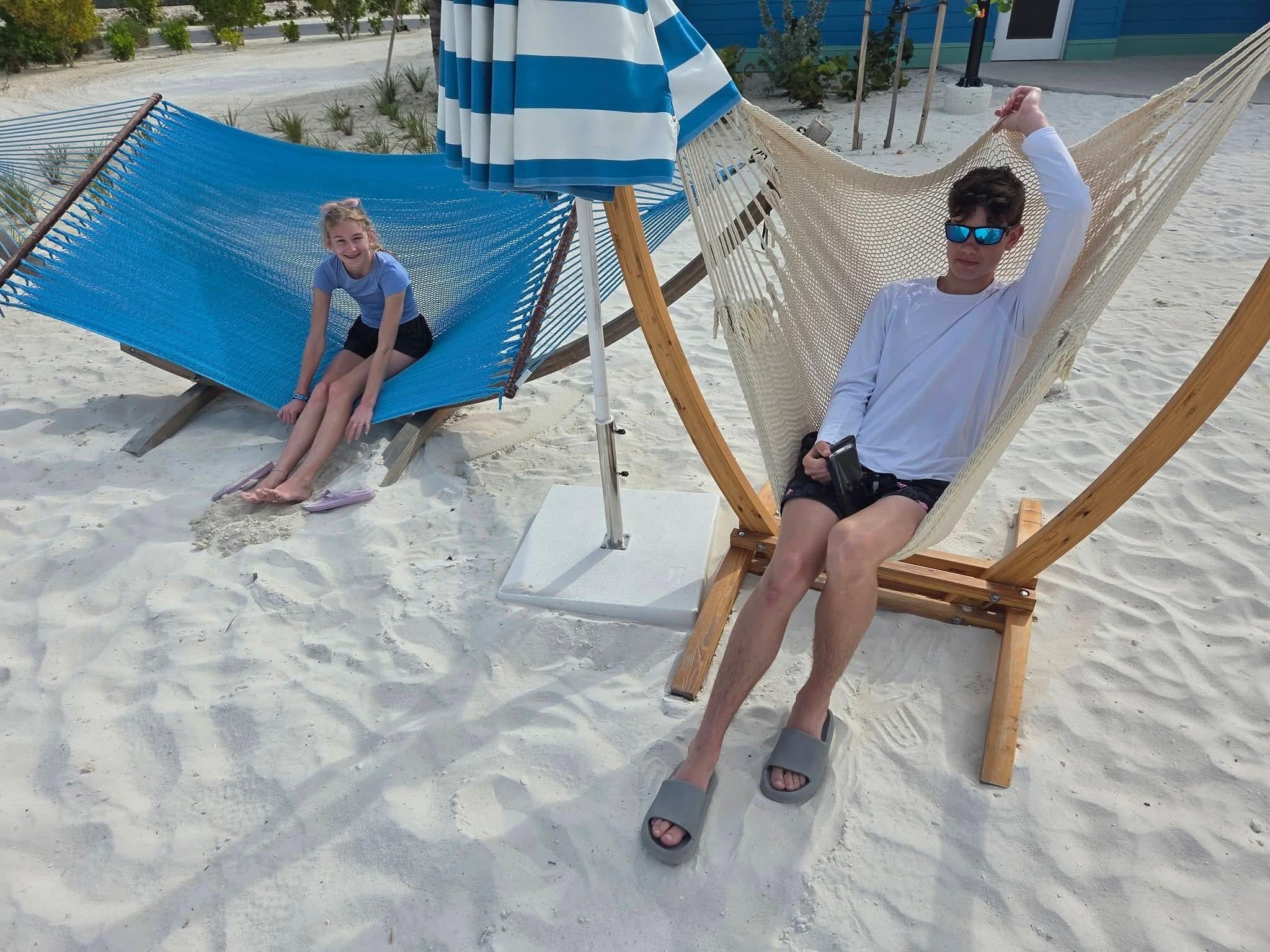 A man and woman sitting in hammocks on a beach