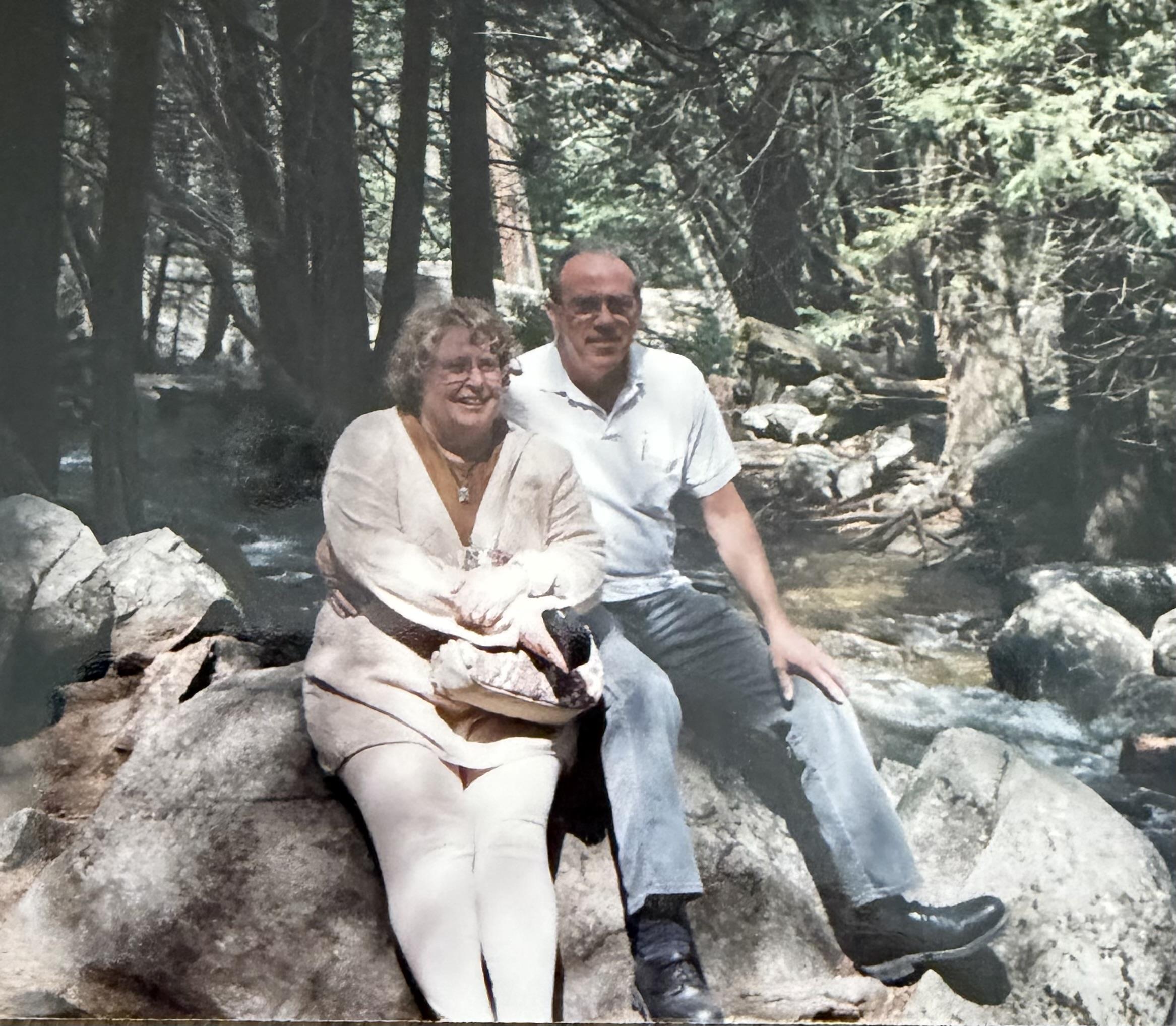A man and woman sitting on rocks in the woods