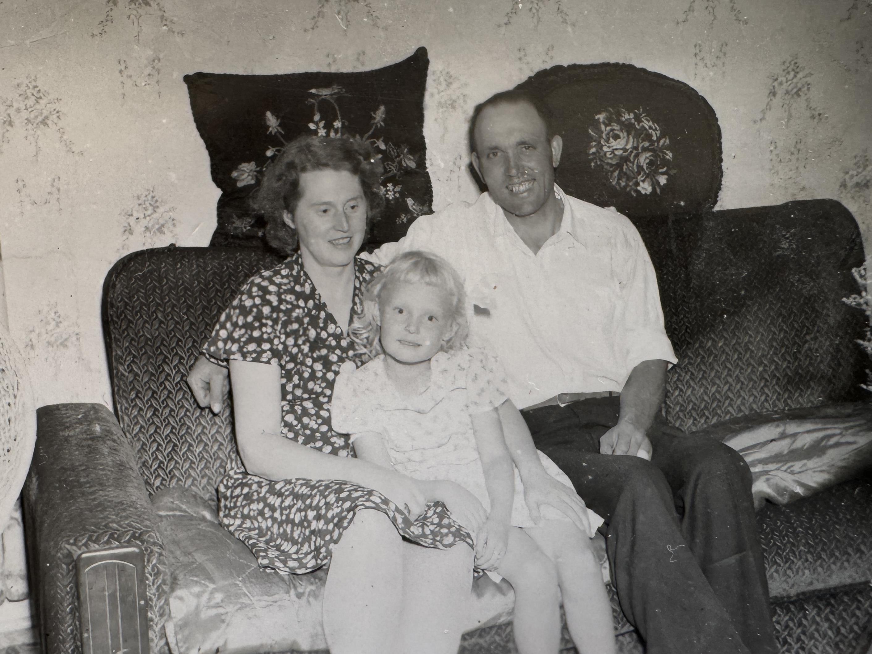 A man and woman sitting on a couch with a child