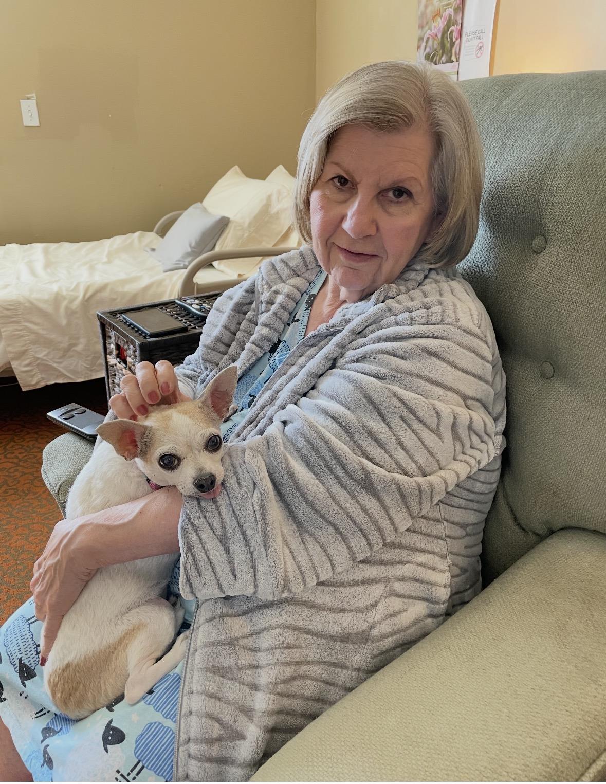 A woman sitting in a chair holding a dog
