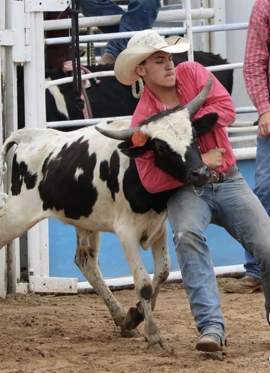 A man in a cowboy hat holding a cow