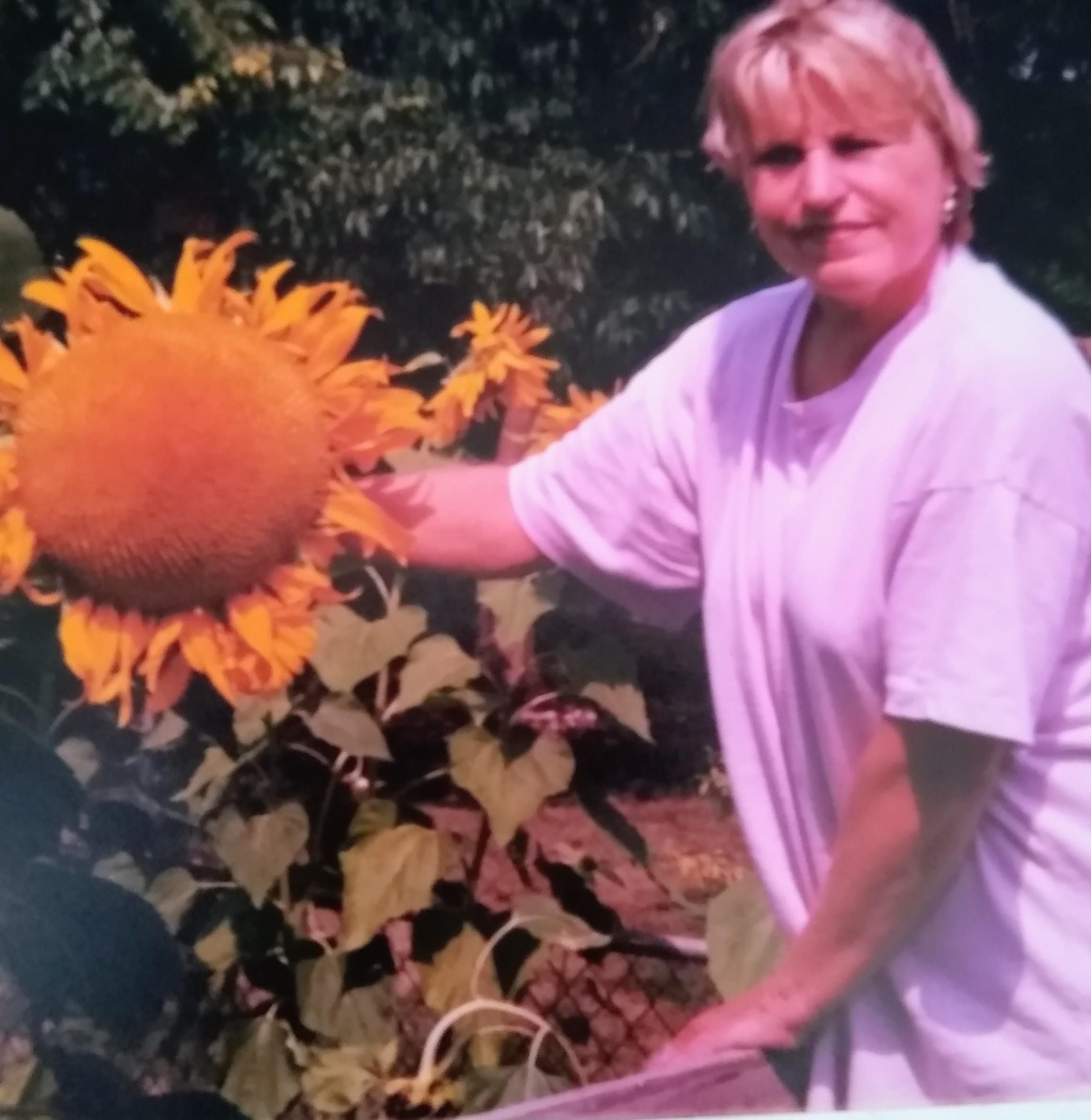 A woman standing next to a sunflower