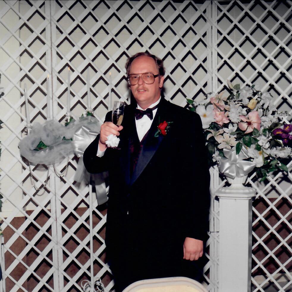 A man in a tuxedo holding a glass of champagne