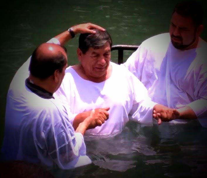A group of men in white robes in a body of water