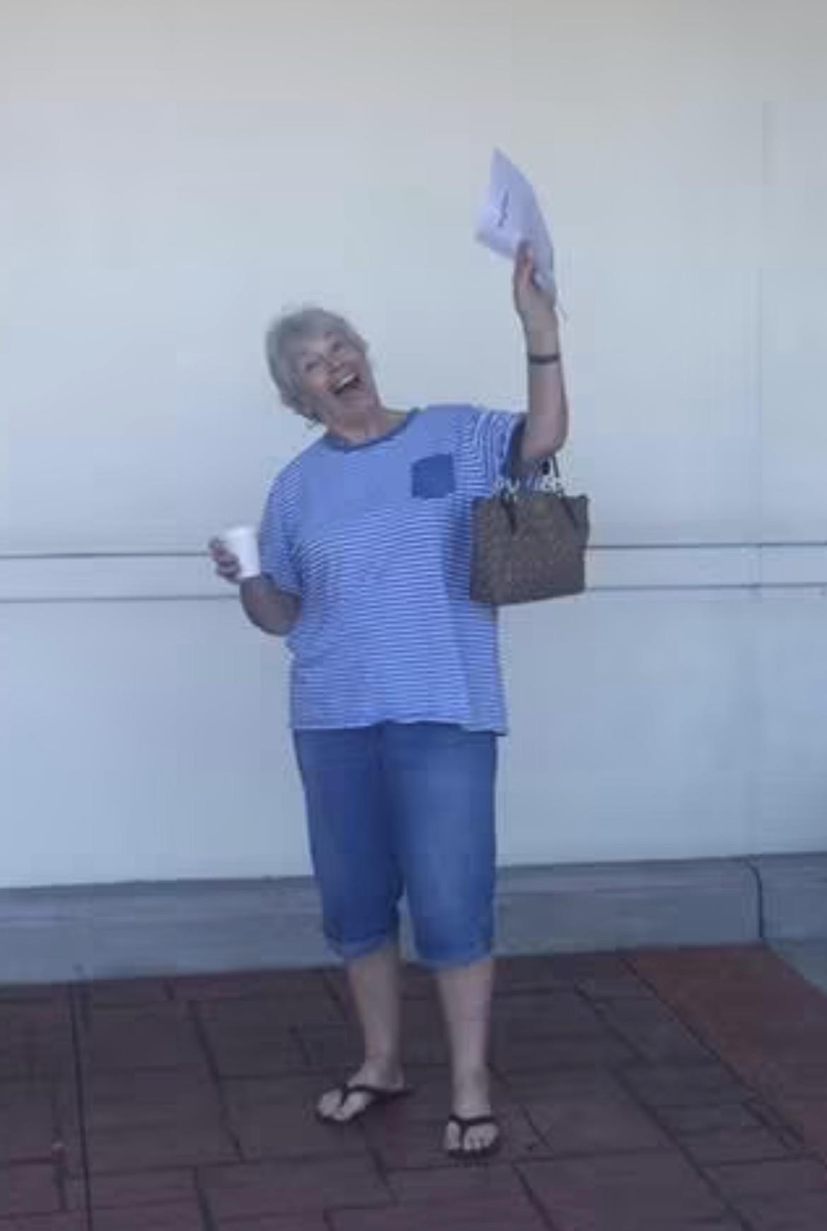 A woman holding a paper and a cup