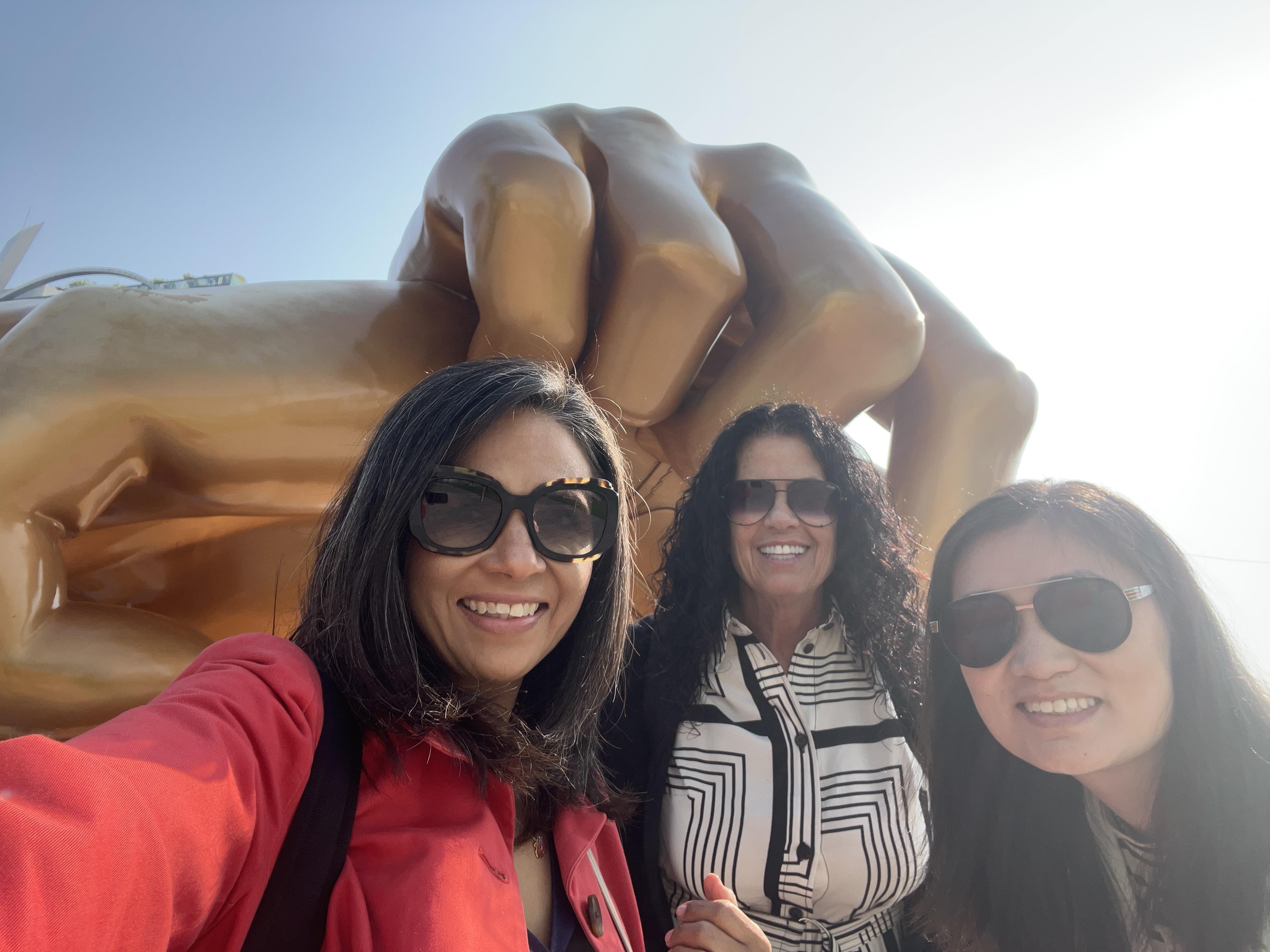 A group of women taking a selfie in front of a large statue