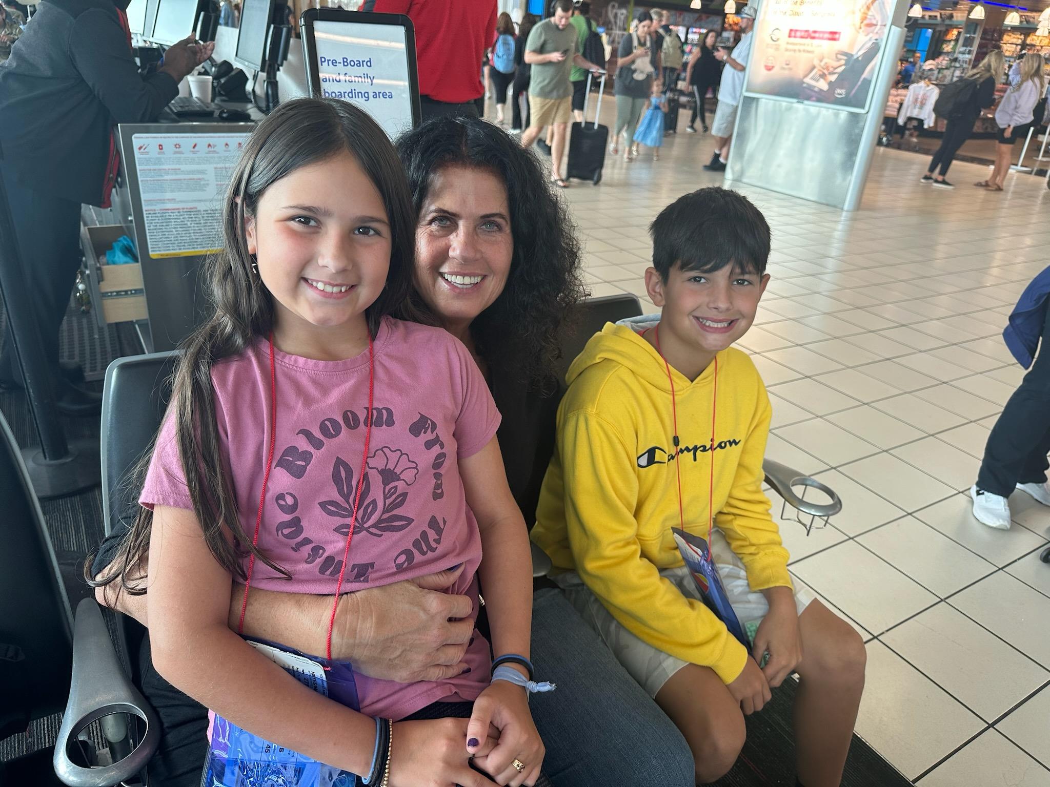 A woman and two children sitting in an airport