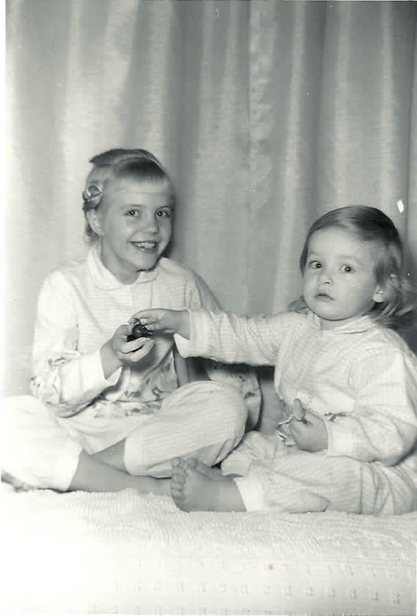 A couple of young girls sitting on a white blanket