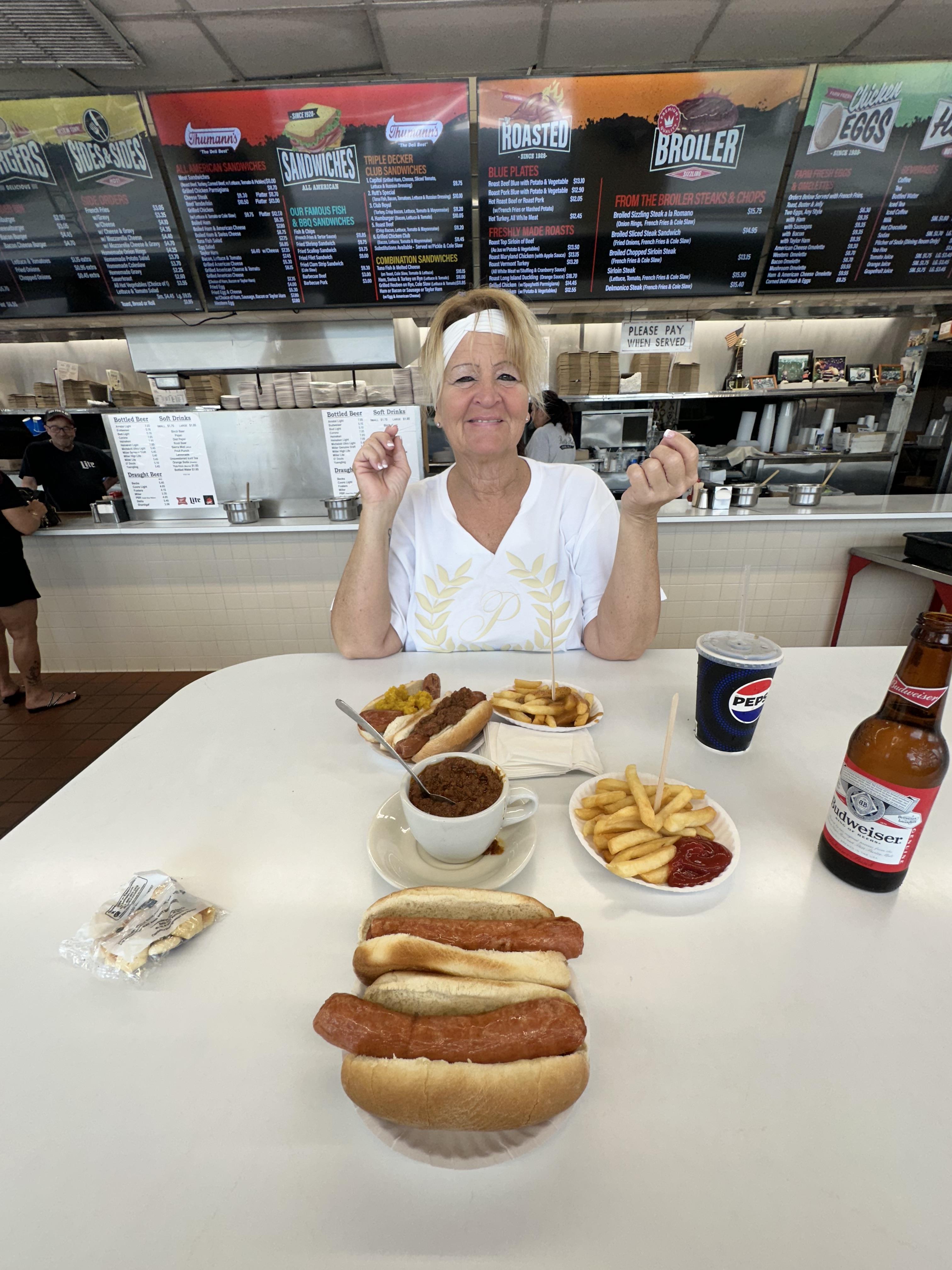 A woman sitting at a table with food and drinks