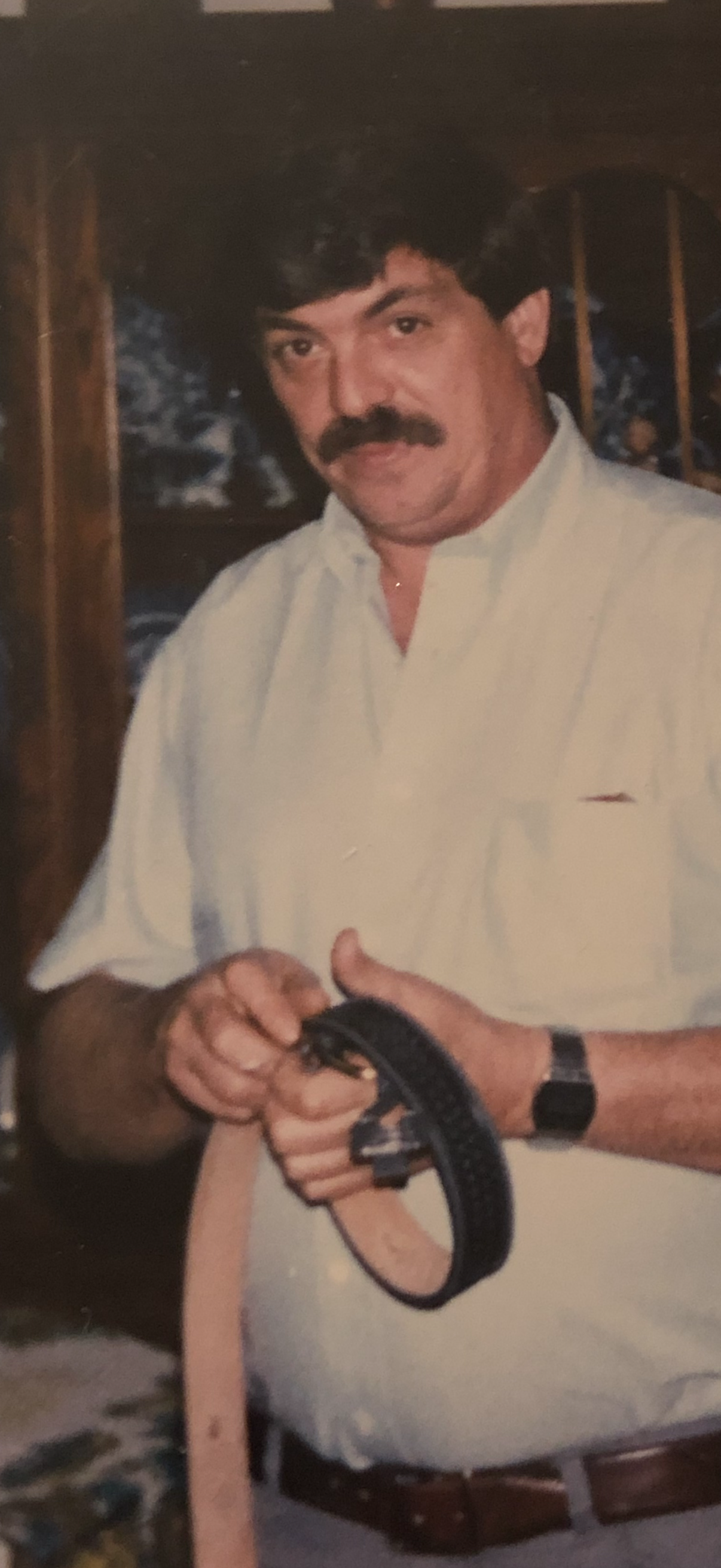 A man with a mustache holding a belt