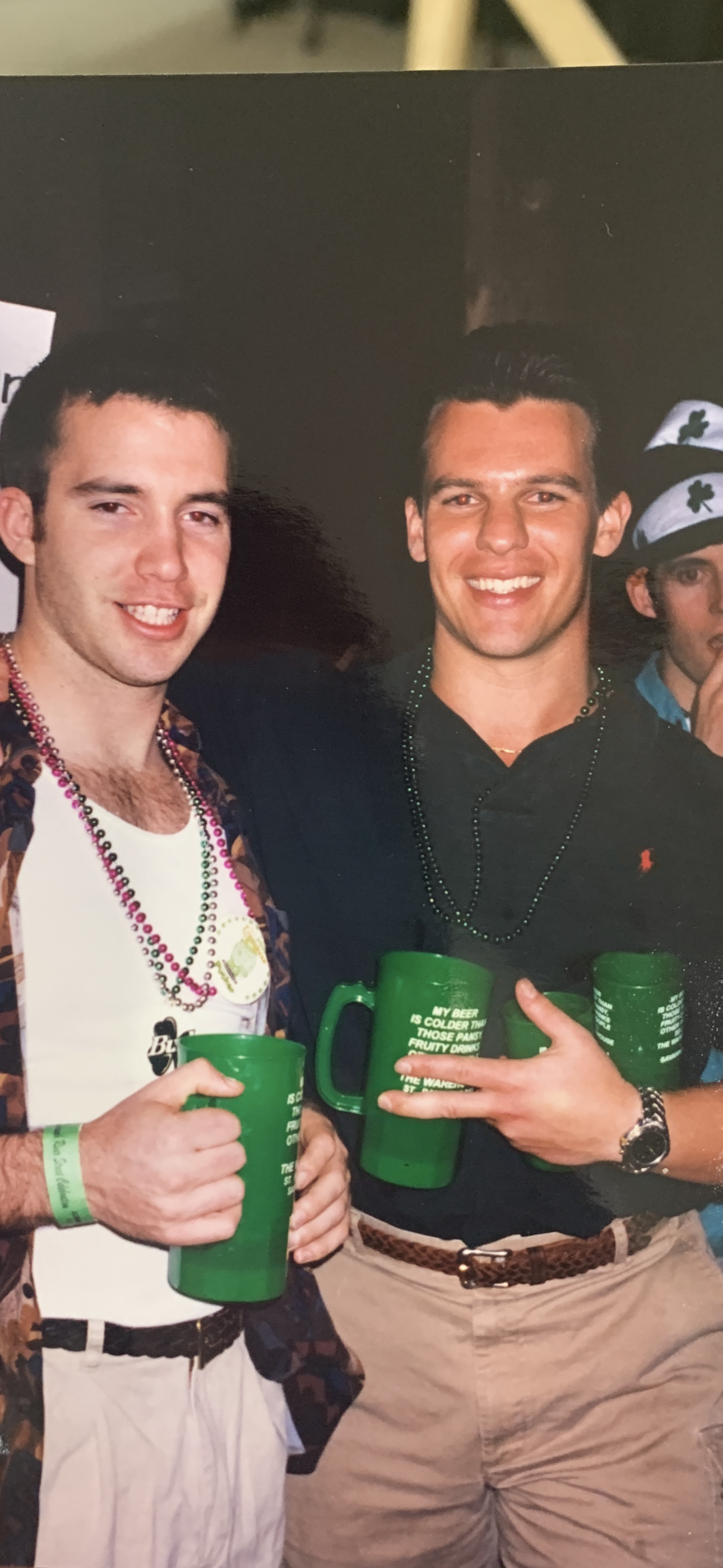 A couple of men holding green cups
