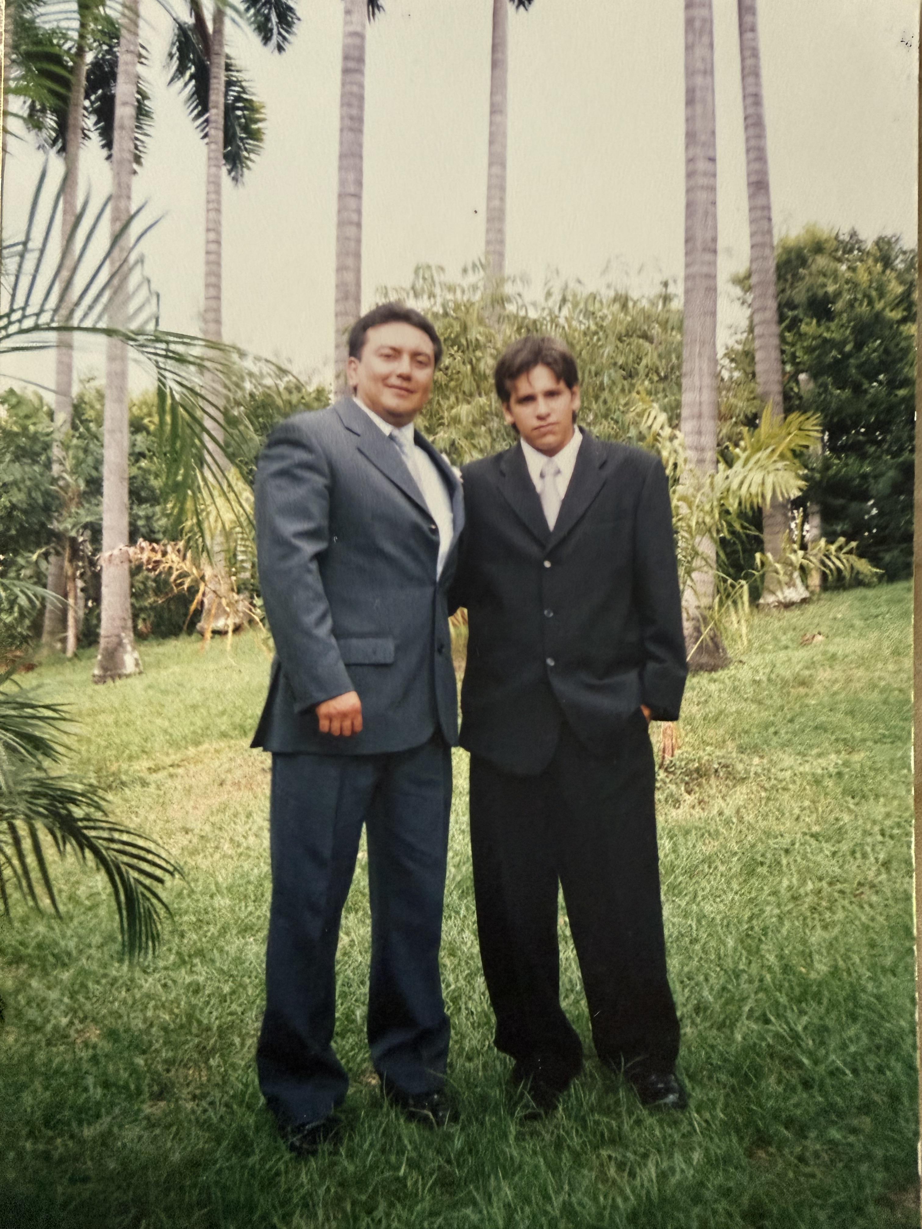 A man and boy in suits standing in a park