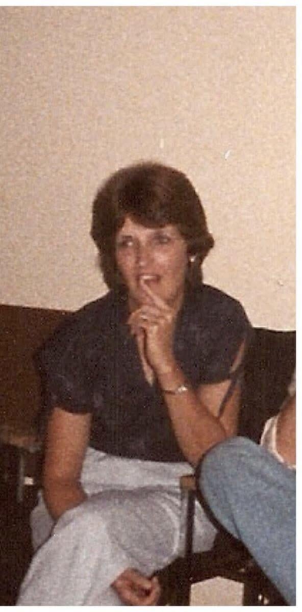 A woman sitting on a couch with her hand on her mouth