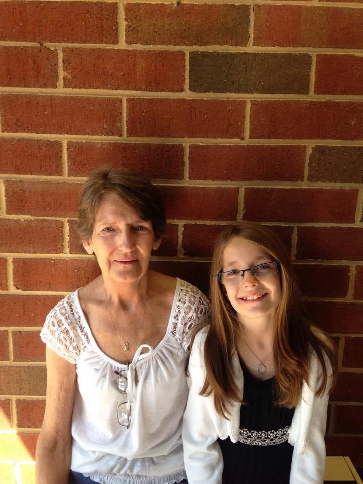 A woman and a girl standing in front of a brick wall