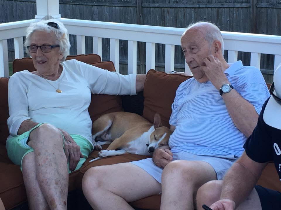 A man and woman sitting on a couch with a dog