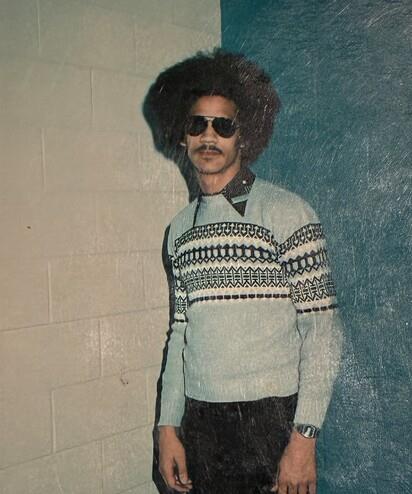 A man wearing sunglasses and a sweater