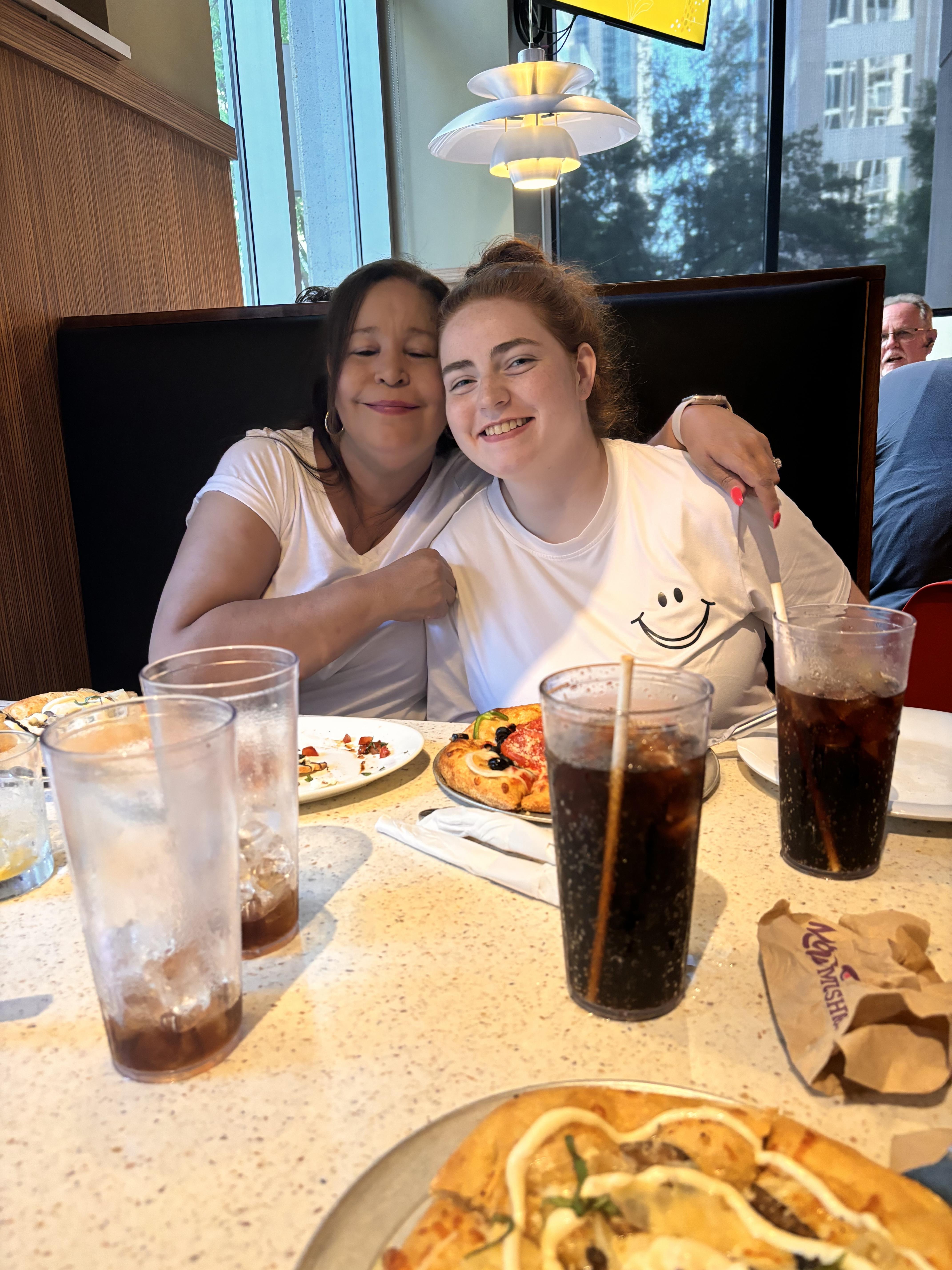 Two women sitting at a table with food and drinks