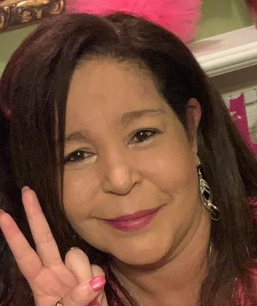 A woman smiling with a peace sign