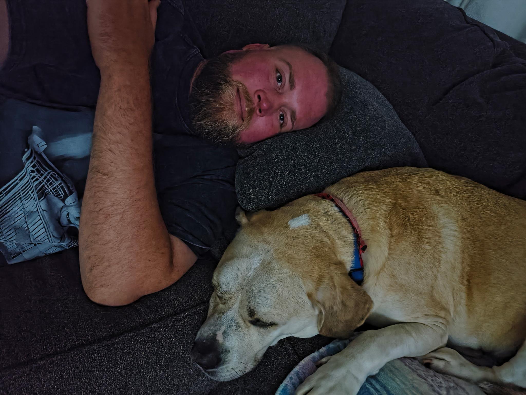 A man lying on a couch with a dog