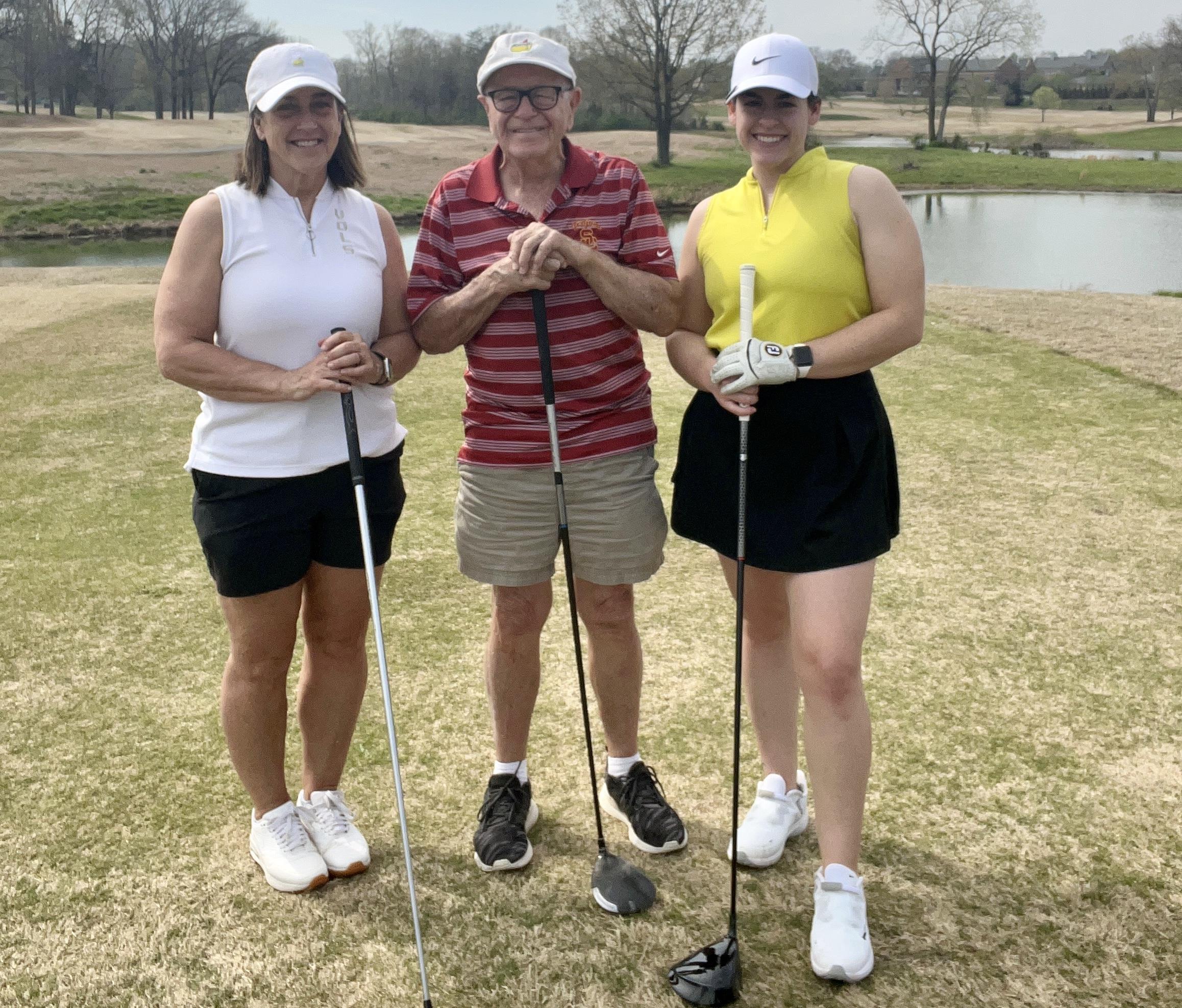 A group of people standing on a golf course
