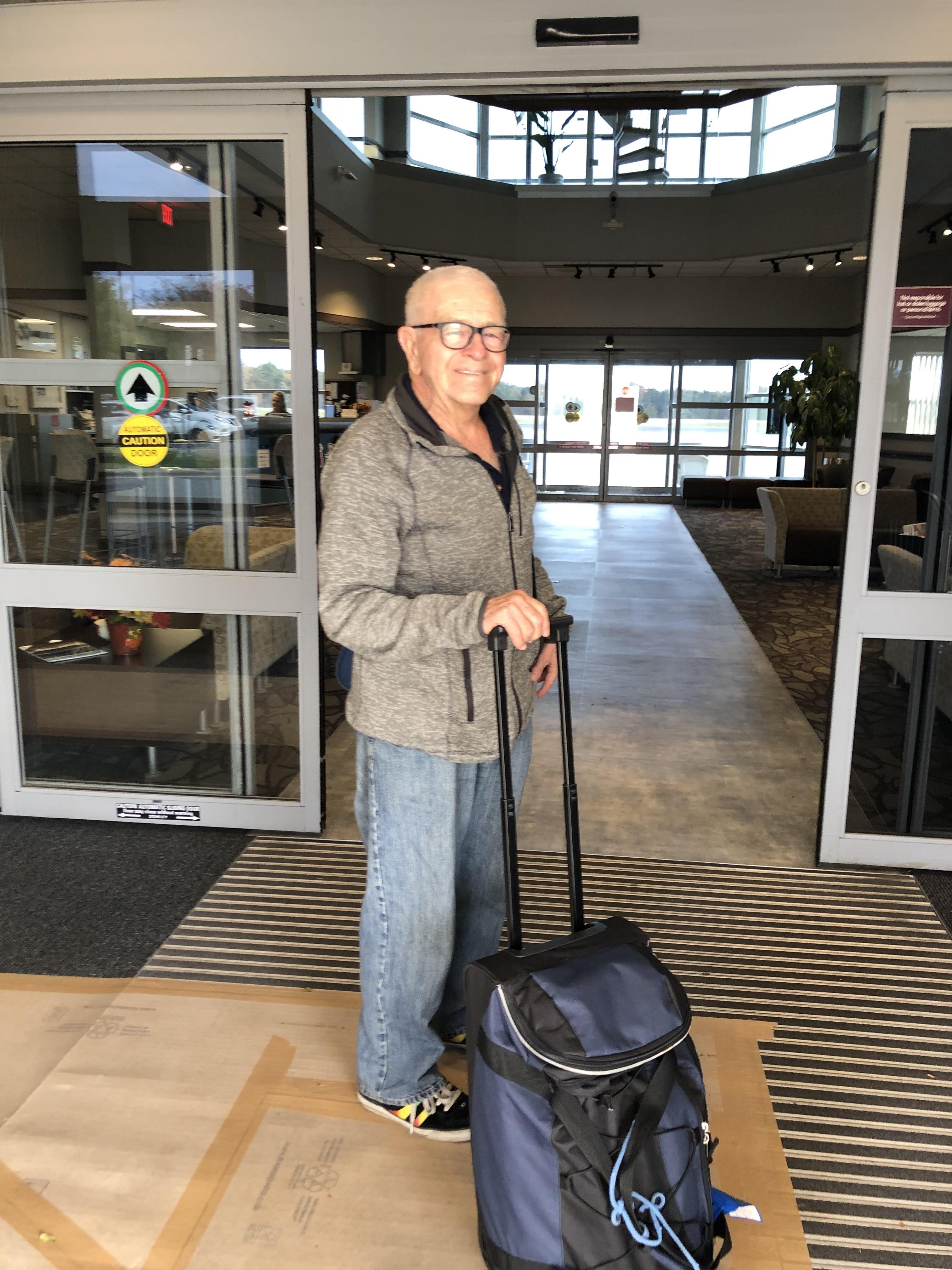 A man with a suitcase in front of a building