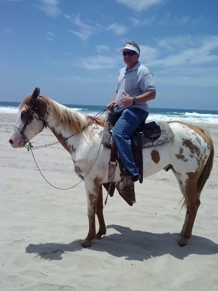 A man riding a horse on the beach