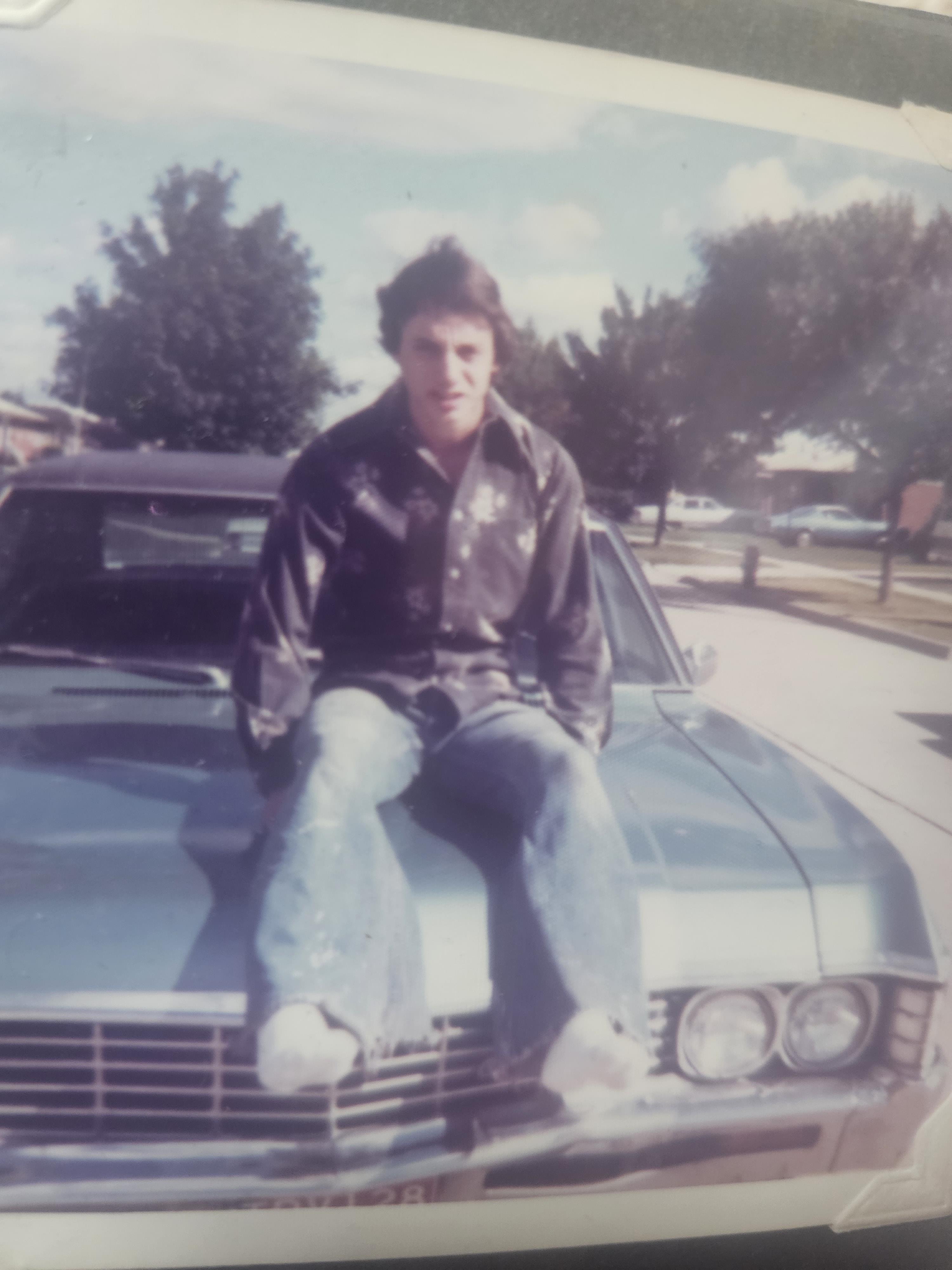 A man sitting on the hood of a car