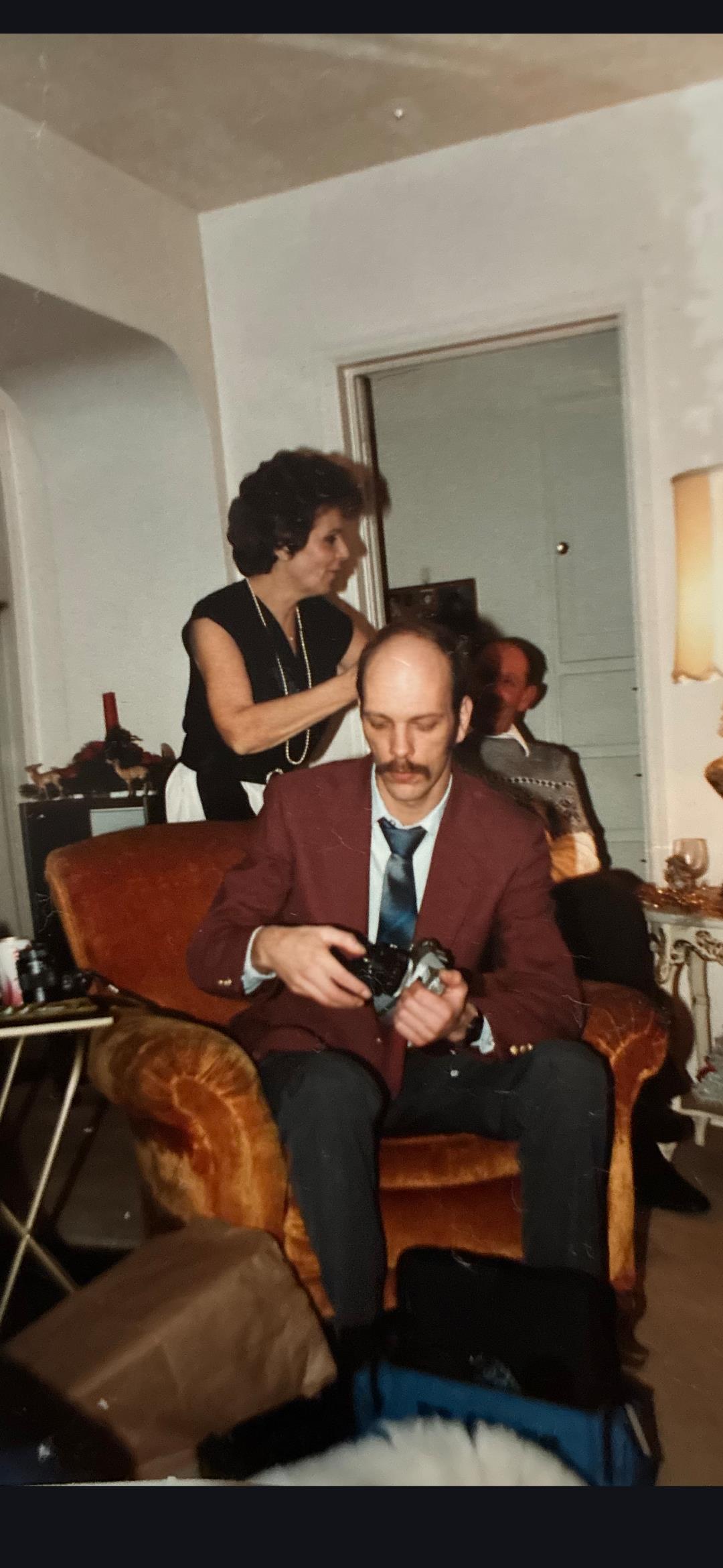 A man sitting in a chair with a woman combing his hair