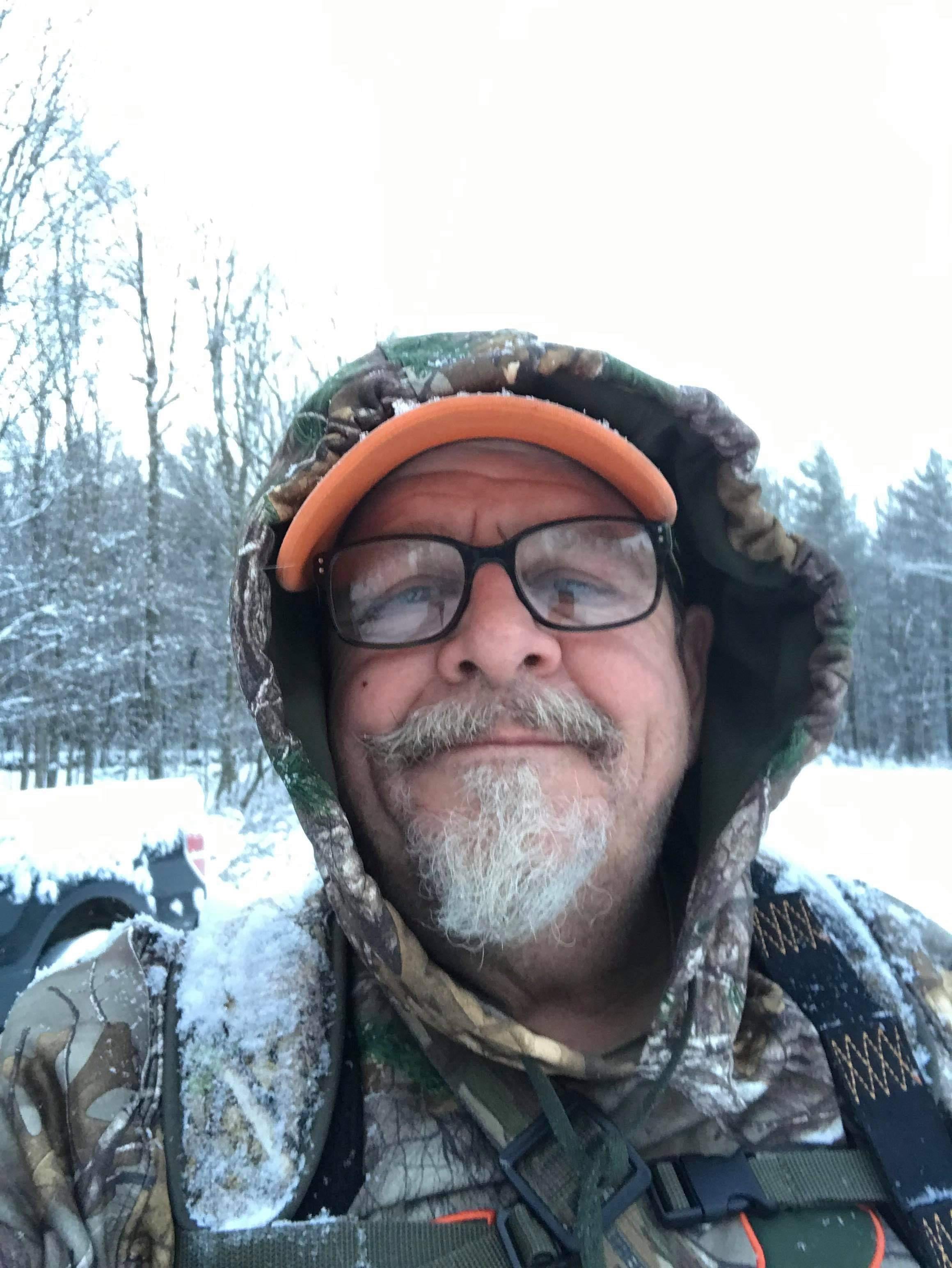 A man in a camouflage hoodie and glasses