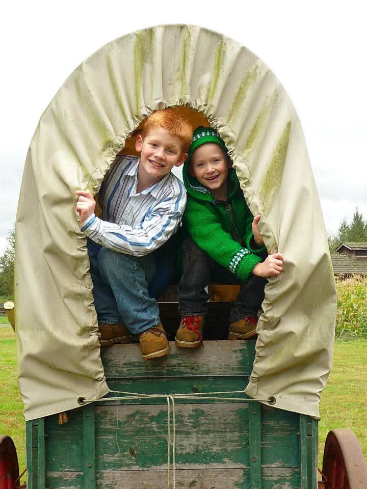A couple of children sitting in a covered wagon
