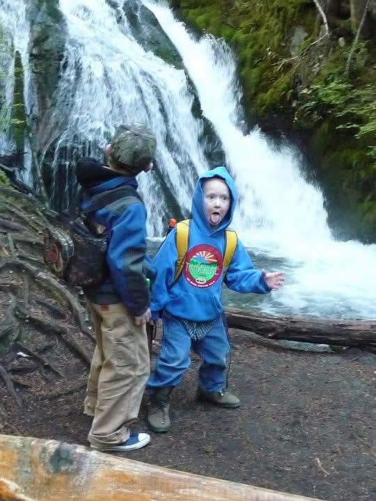 Two children standing next to a waterfall