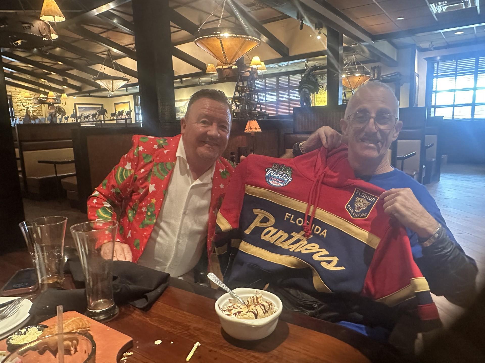 Two men sitting at a table with a jersey