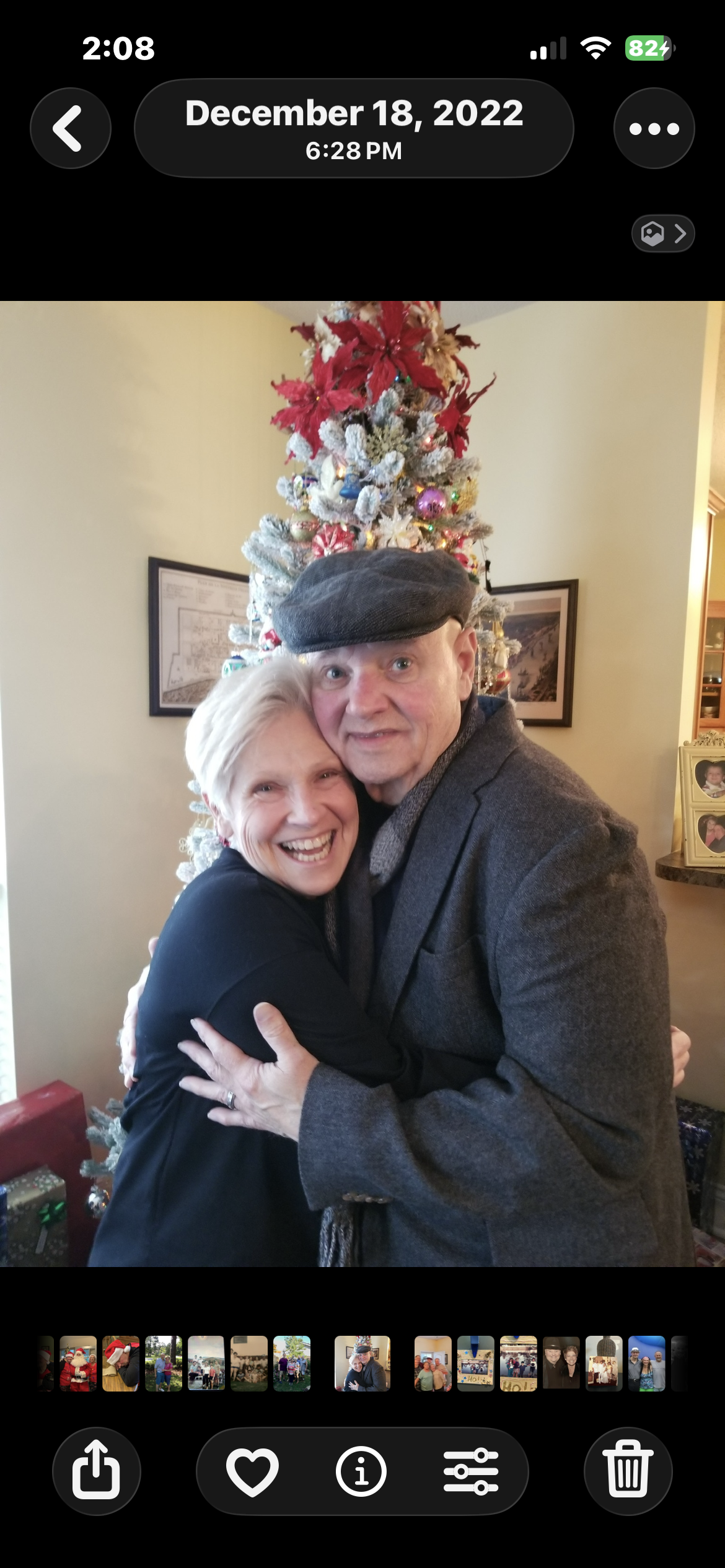 A man and woman hugging in front of a christmas tree