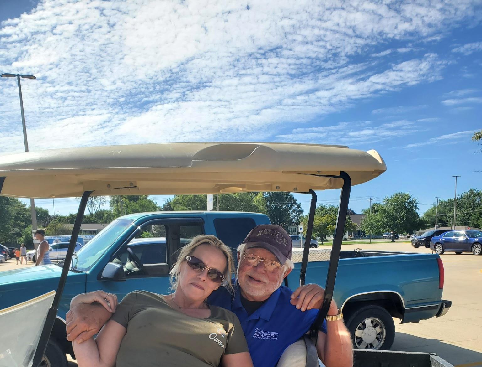 A man and woman sitting in a golf cart