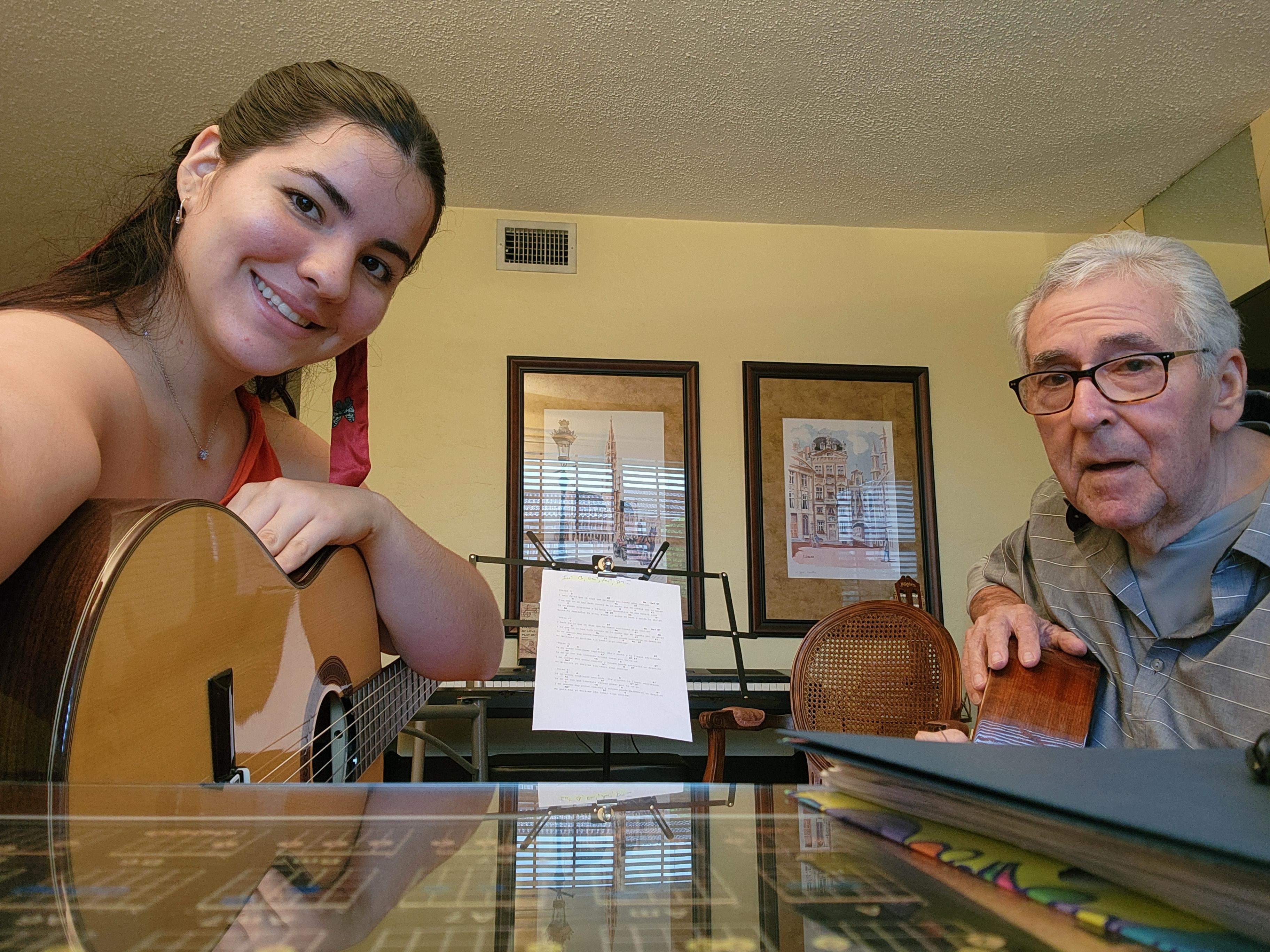 A woman playing a guitar with an old man