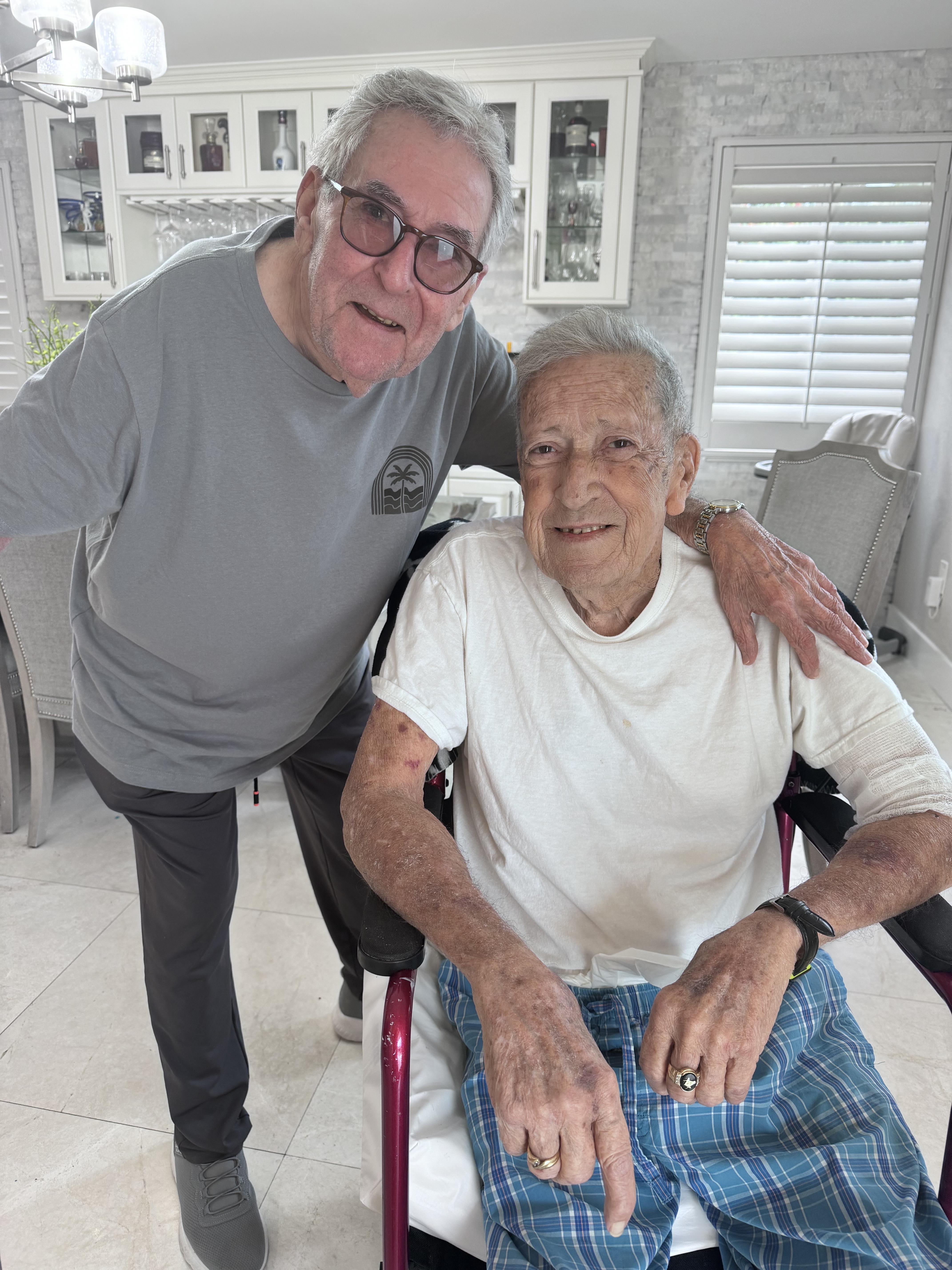A man standing next to an older man in a wheelchair