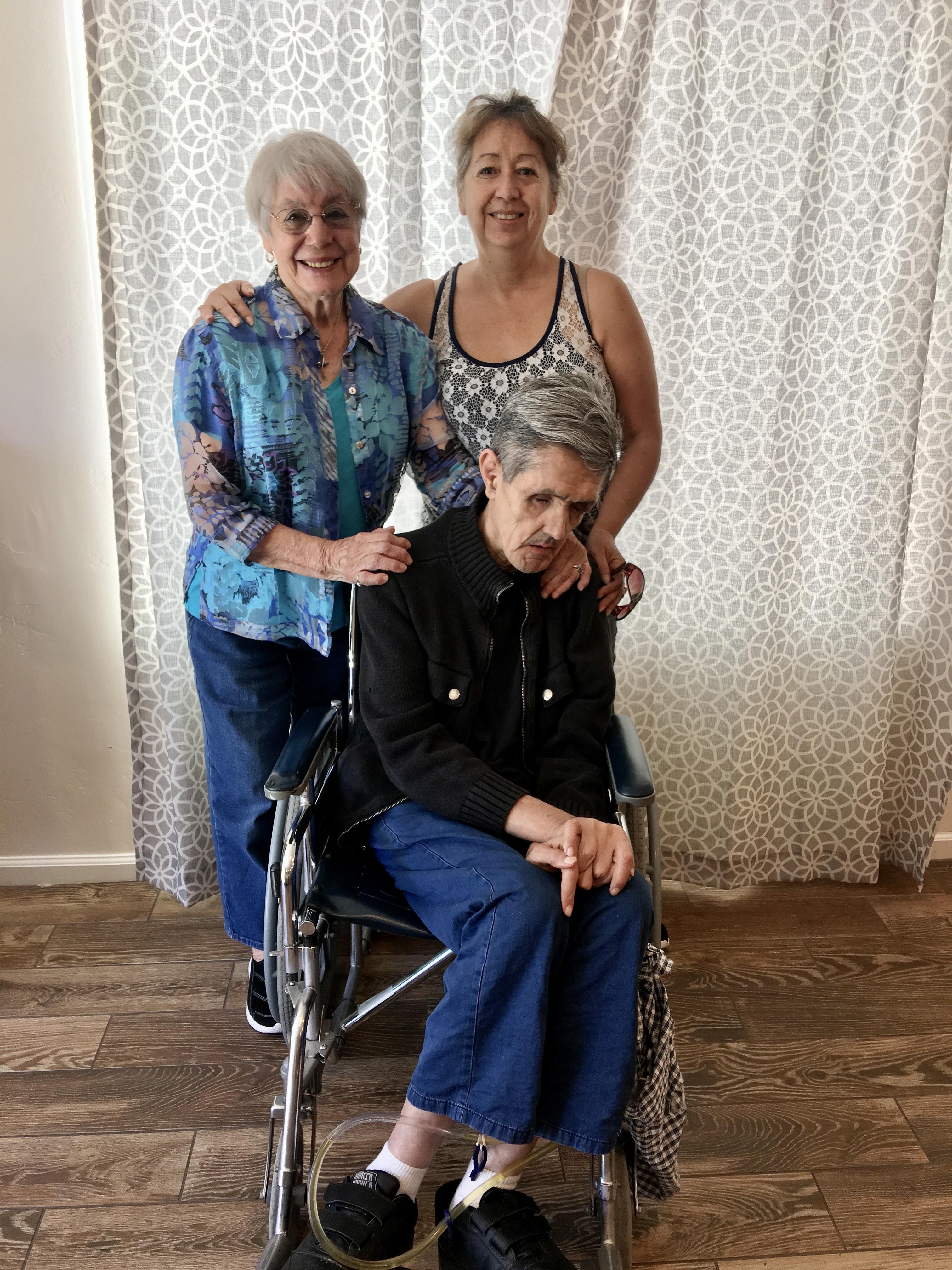 A group of women standing next to a man in a wheelchair