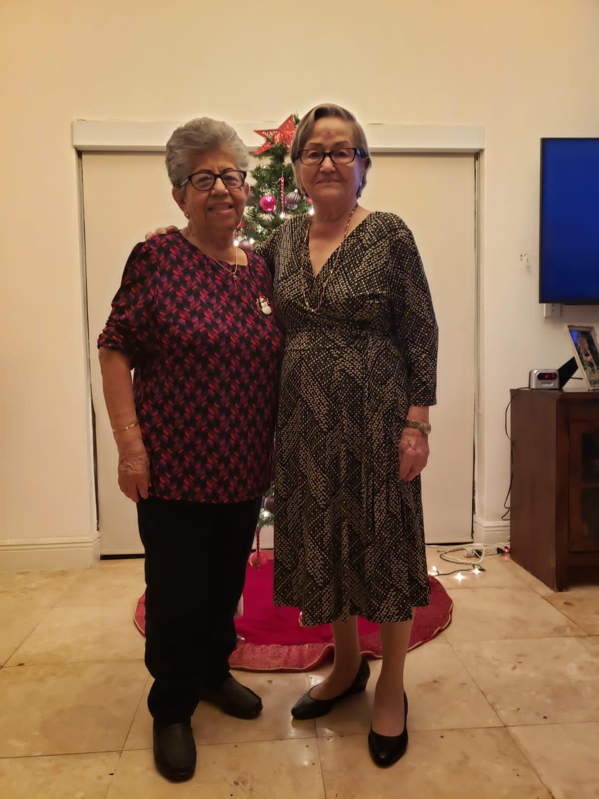 Two women standing in front of a christmas tree