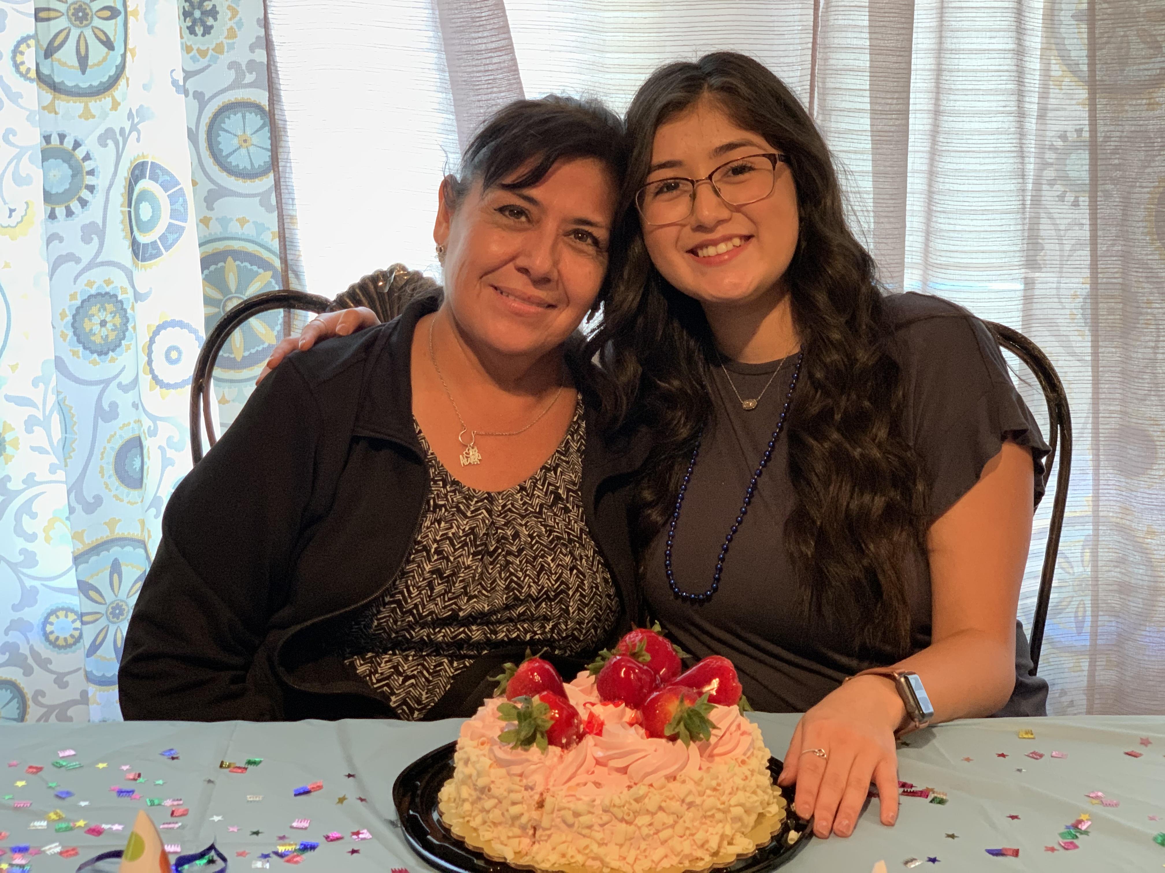 Two women sitting at a table with a cake