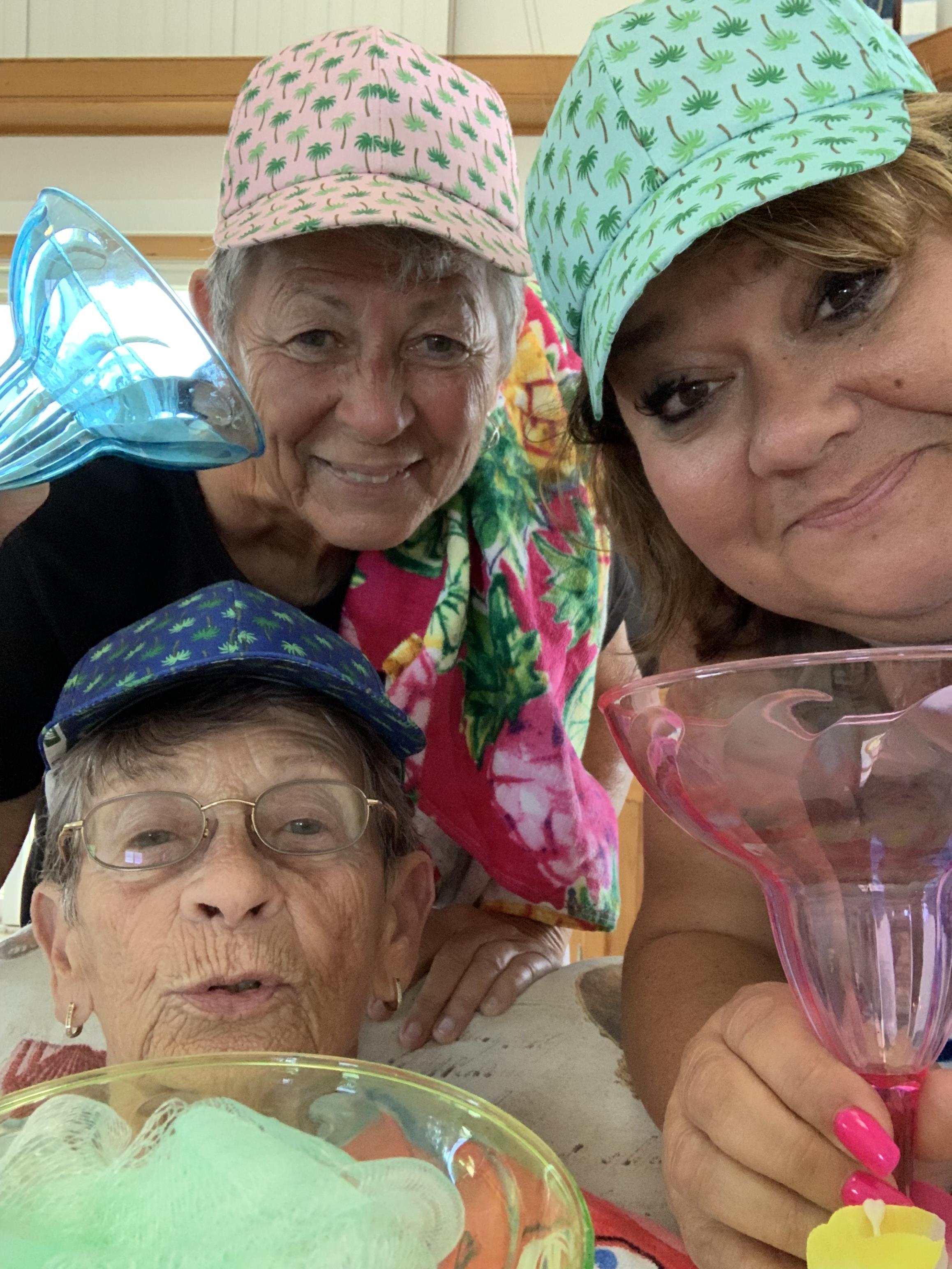 A group of women wearing hats and drinking