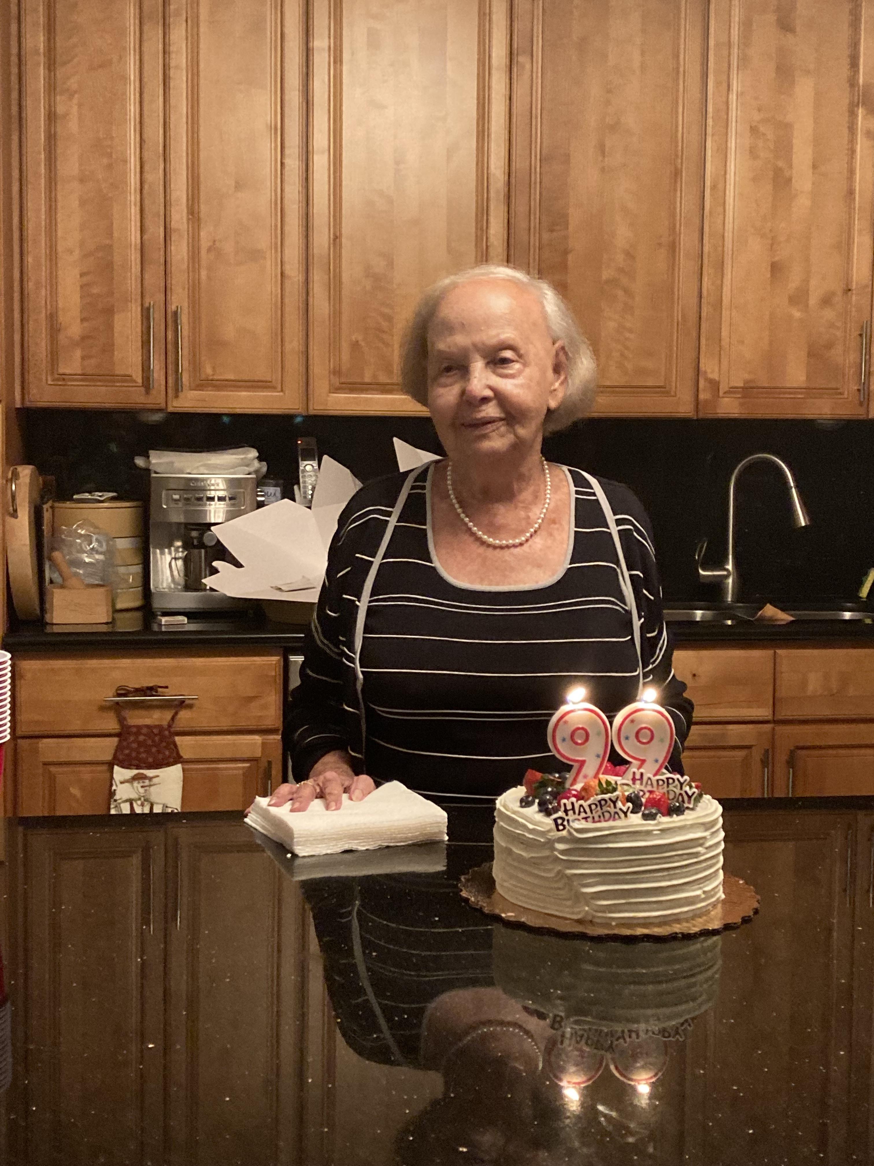 An old woman standing in front of a cake
